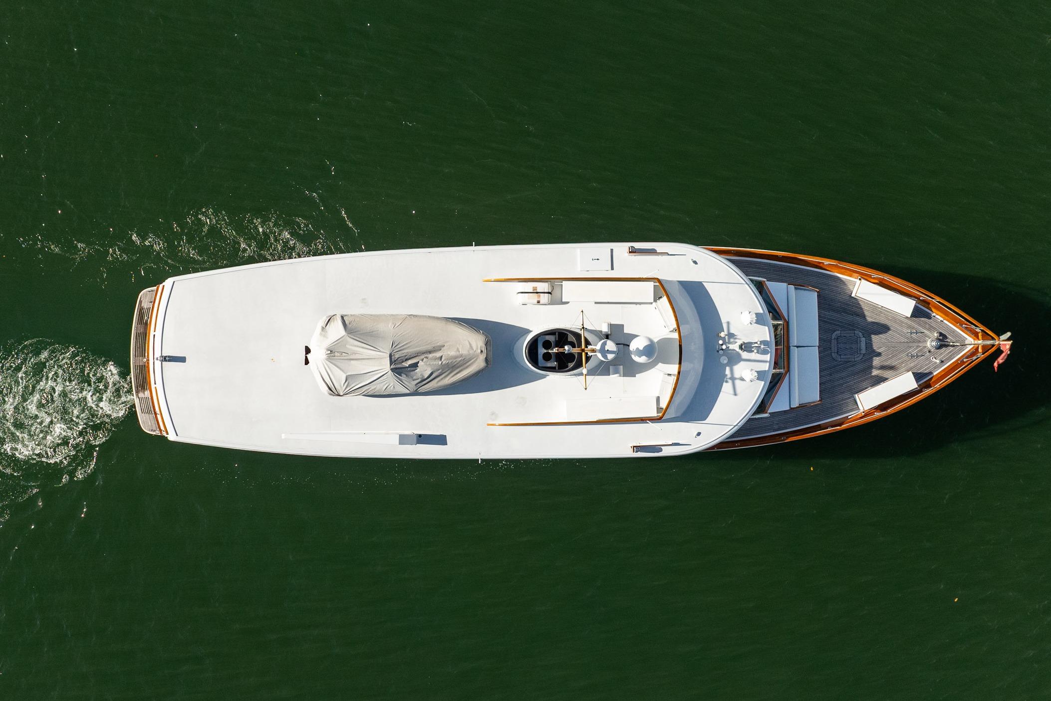 Aerial view of 1972 Trumpy 72 Motor Yacht cruising on green water.