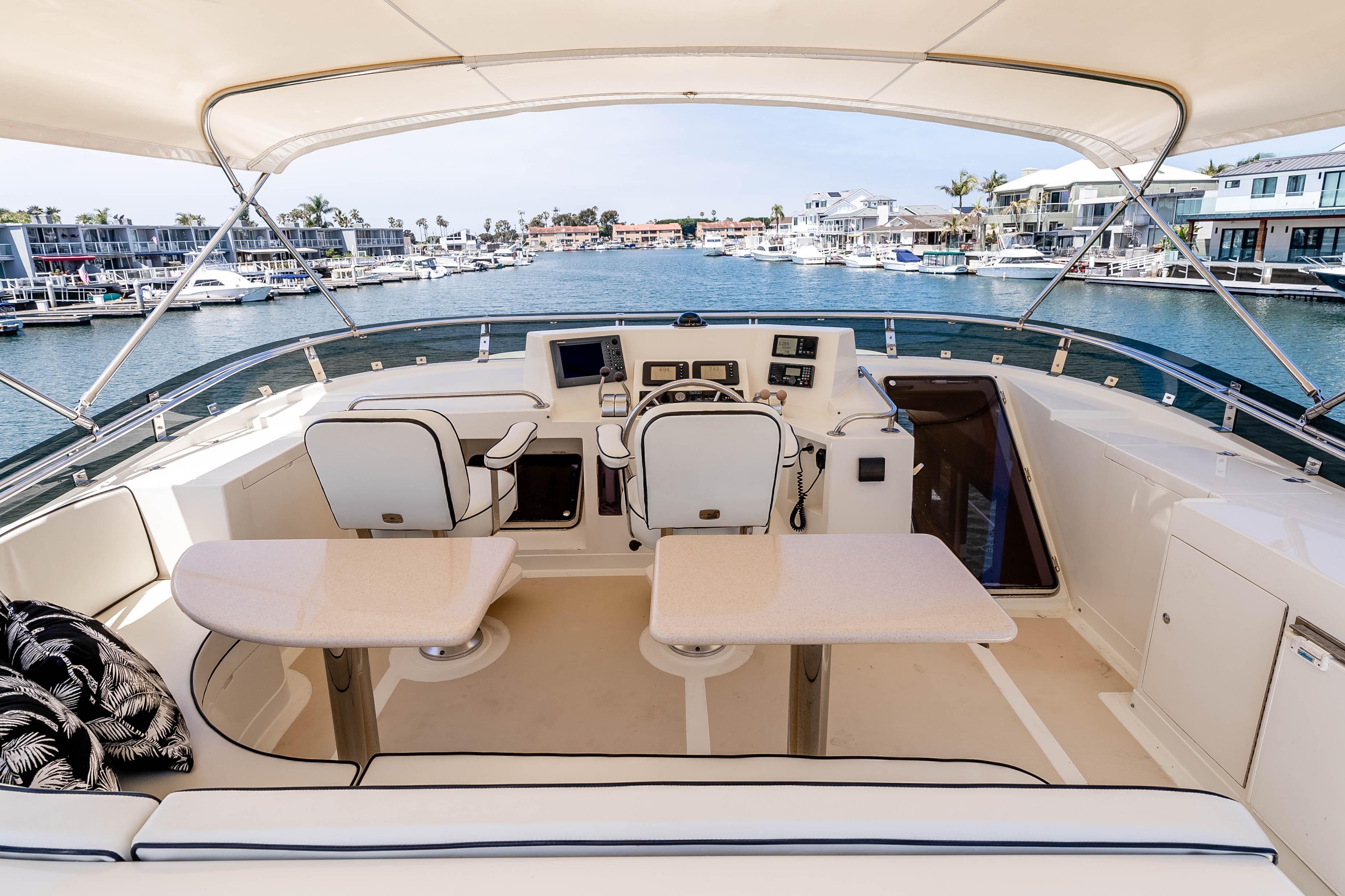 Pilothouse of 2005 Offshore Yachts 54, featuring helm and seating, overlooking marina.