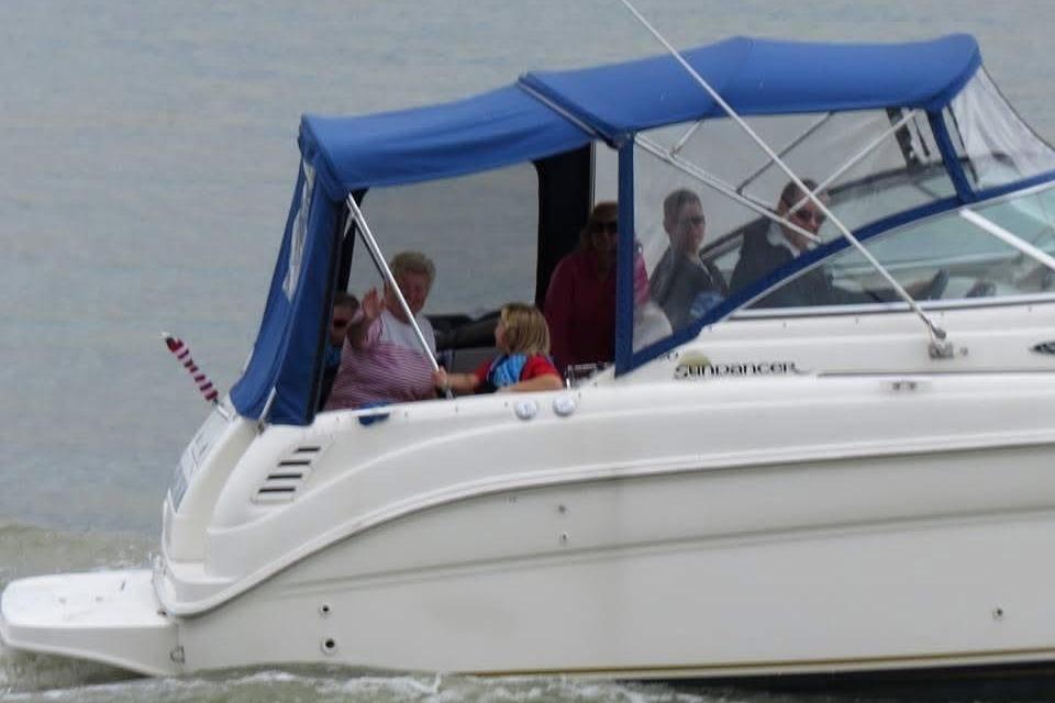 2003 Sea Ray 260 Sundancer boat with blue canopy cruising on water.