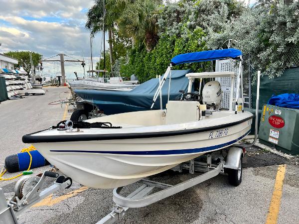 1986 Hoog Comet 14 boat on trailer with blue canopy in marina.