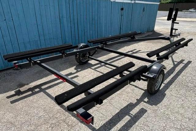 2023 Yacht Club 18' Pontoon trailer parked on gravel near blue wooden fence.