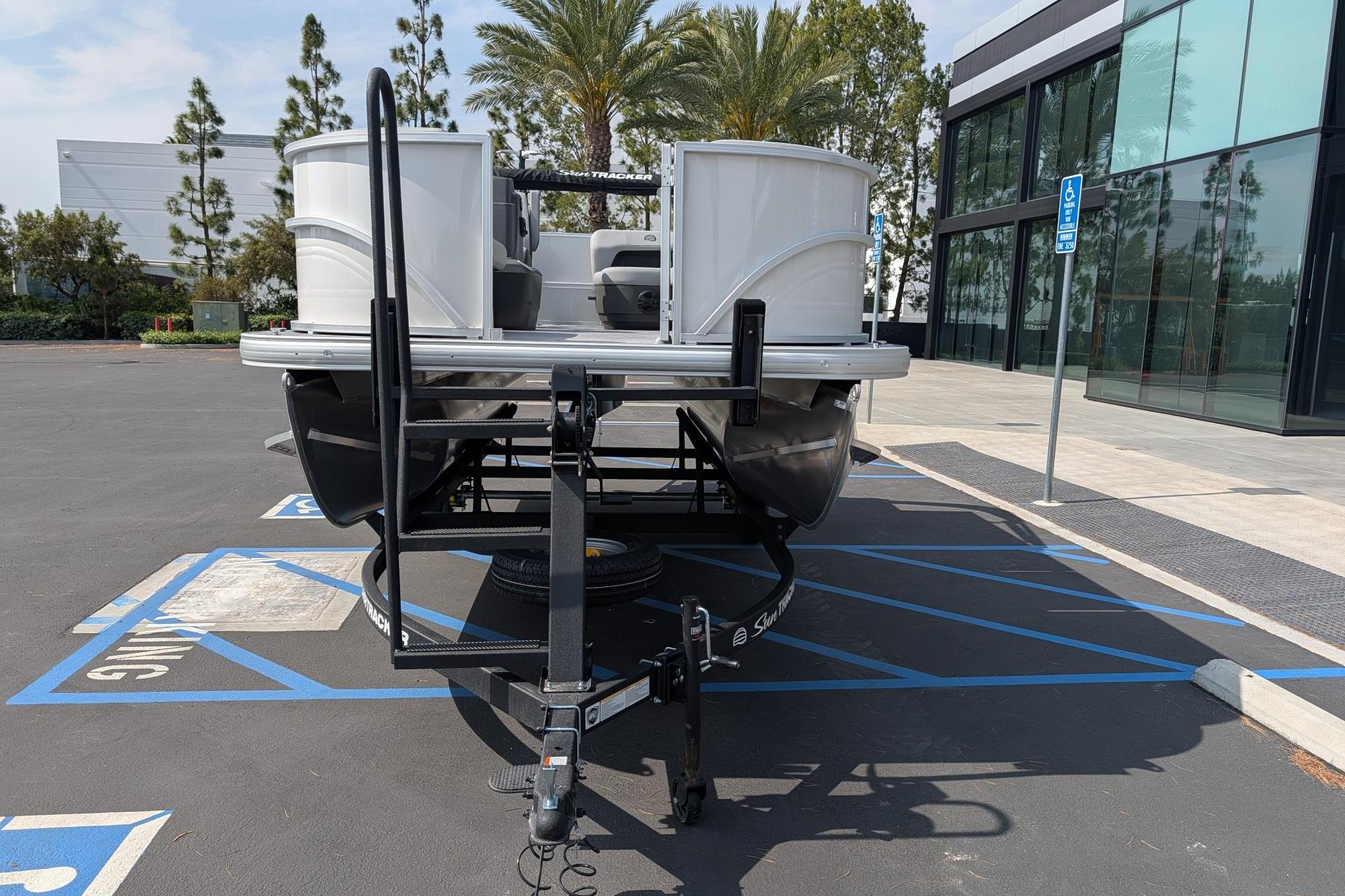 2026 Sun Tracker Party Barge 16 DLX pontoon boat on trailer in parking lot.