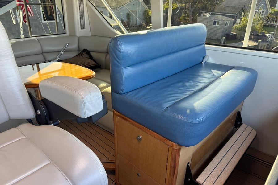 Interior of 2002 Viking 61 Enclosed Bridge yacht with blue seating and wooden accents.