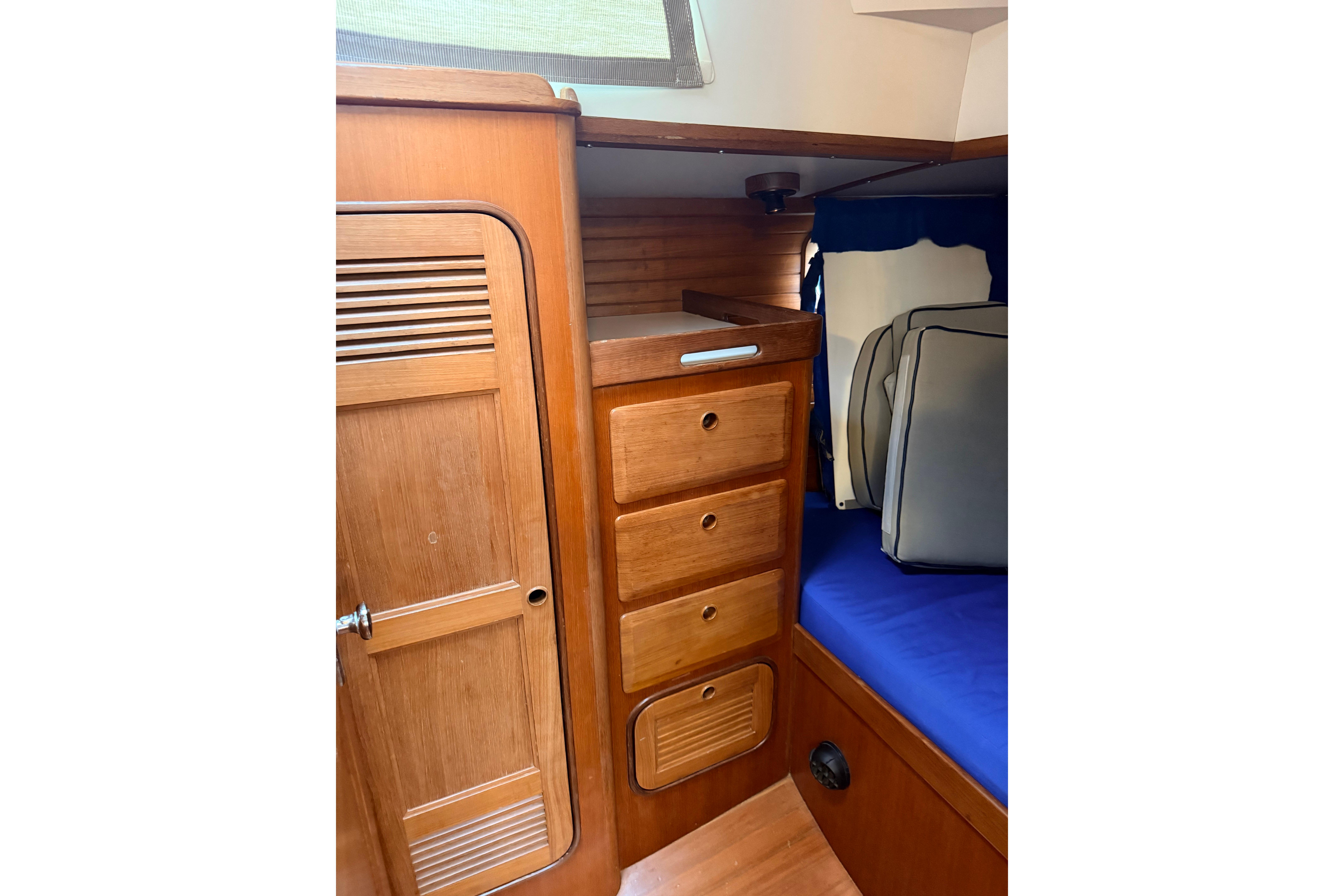Interior of 1987 Norseman 400 sailboat with wooden cabinetry and blue cushions.