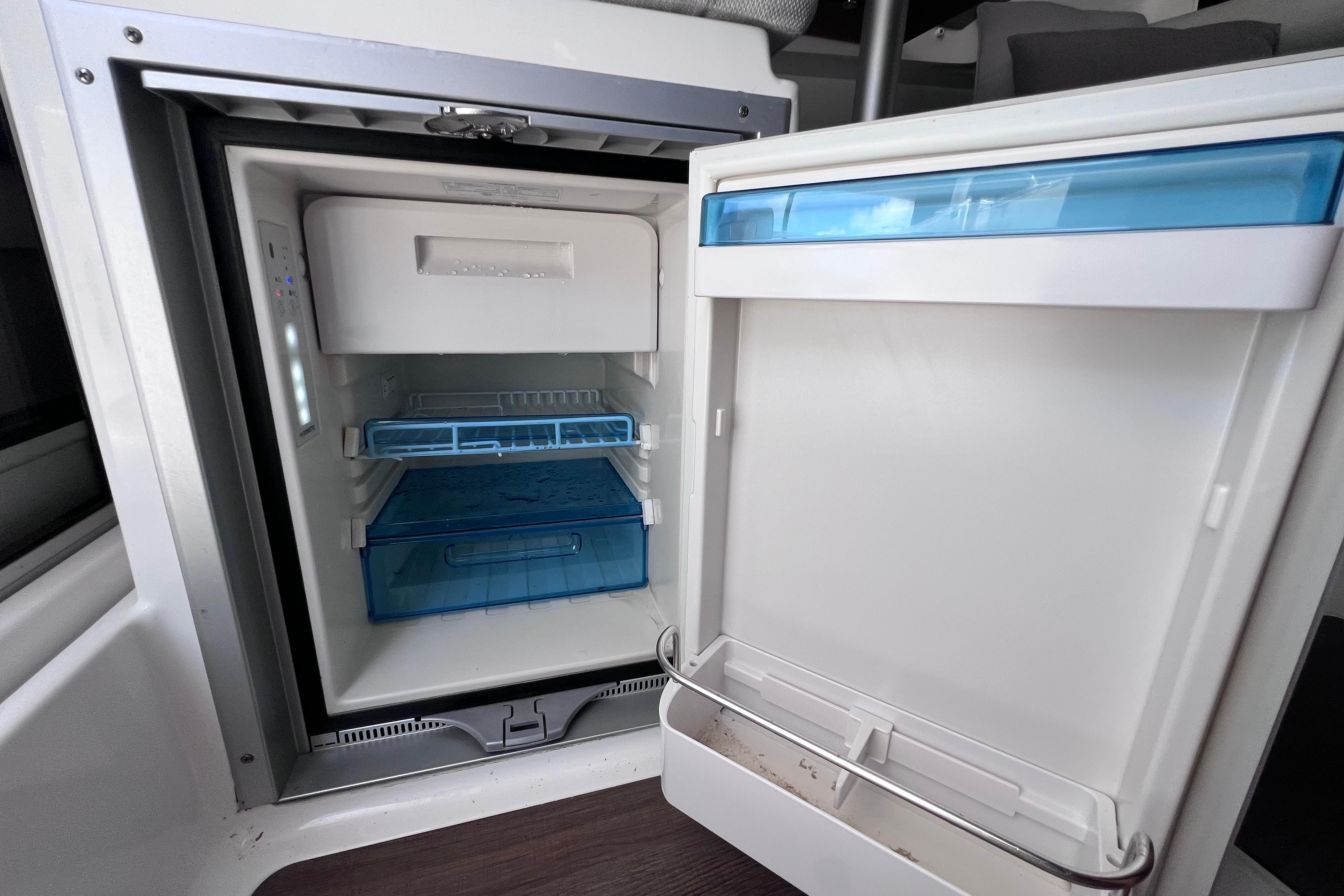Open refrigerator inside 2021 Jeanneau NC Weekender 795 Series 2 boat, showcasing storage compartments.