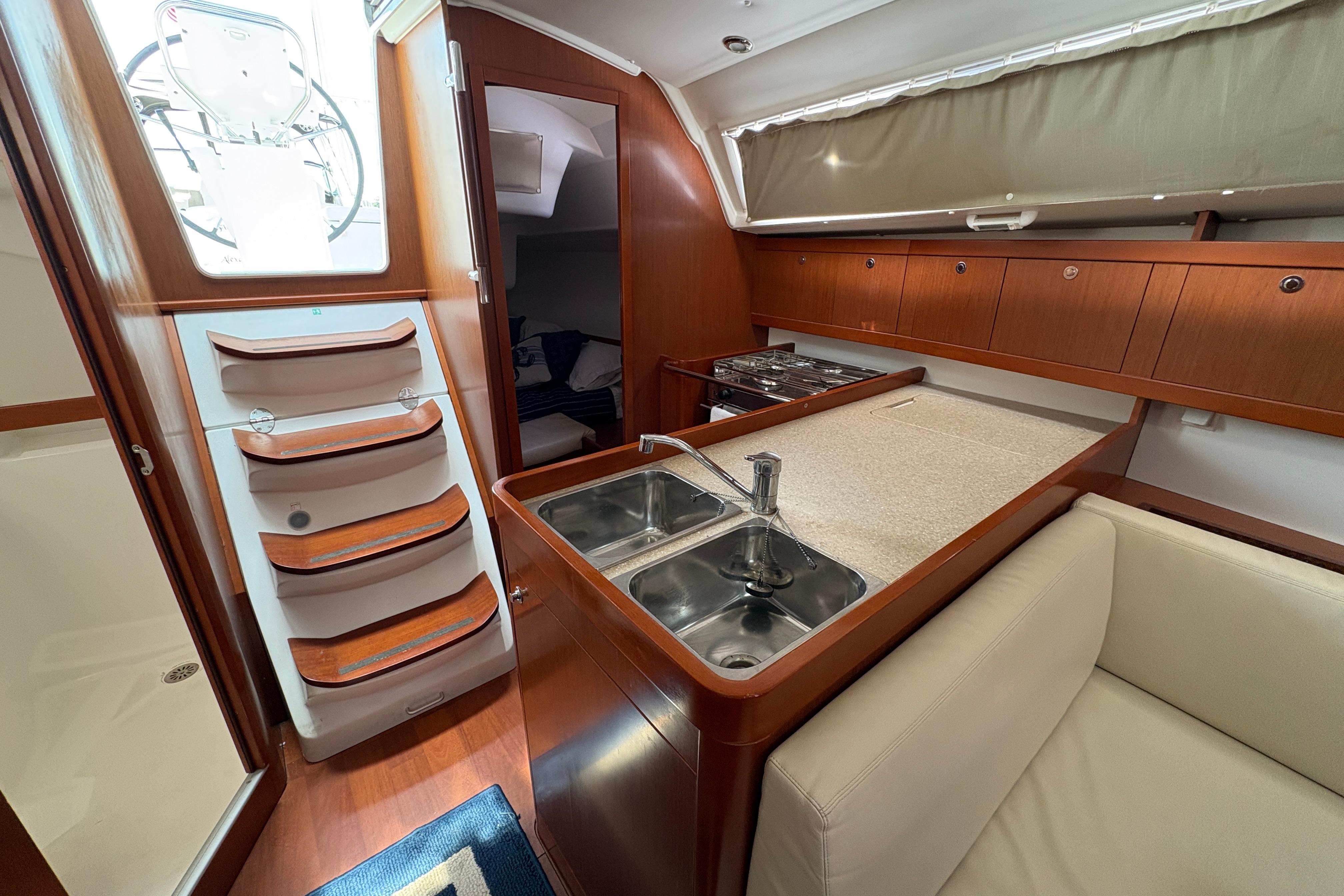 Interior of 2015 Beneteau Oceanis 34 yacht with kitchen, sink, and stairs.