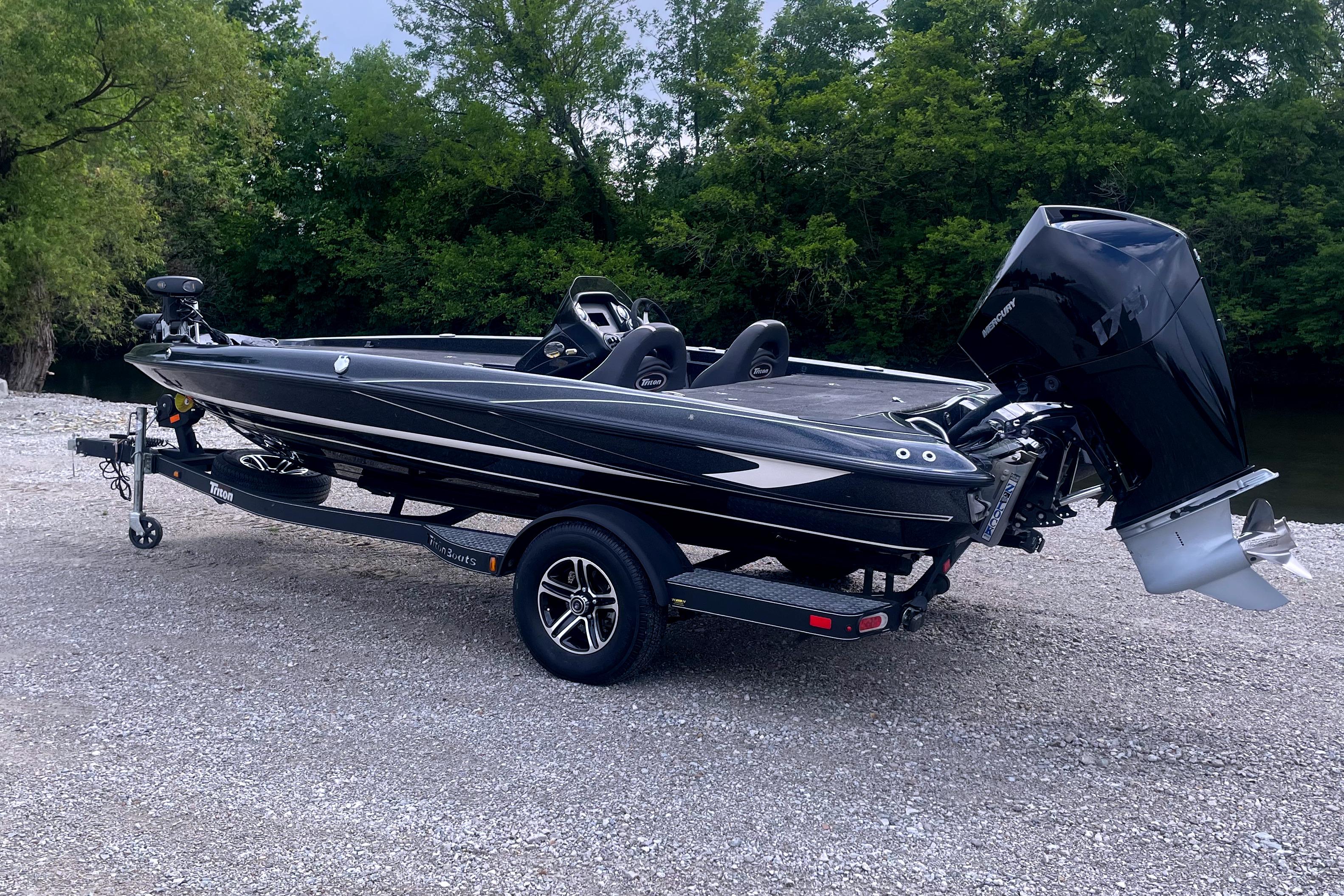 2022 Triton 18 TrX boat on trailer, parked on gravel near lush green trees.