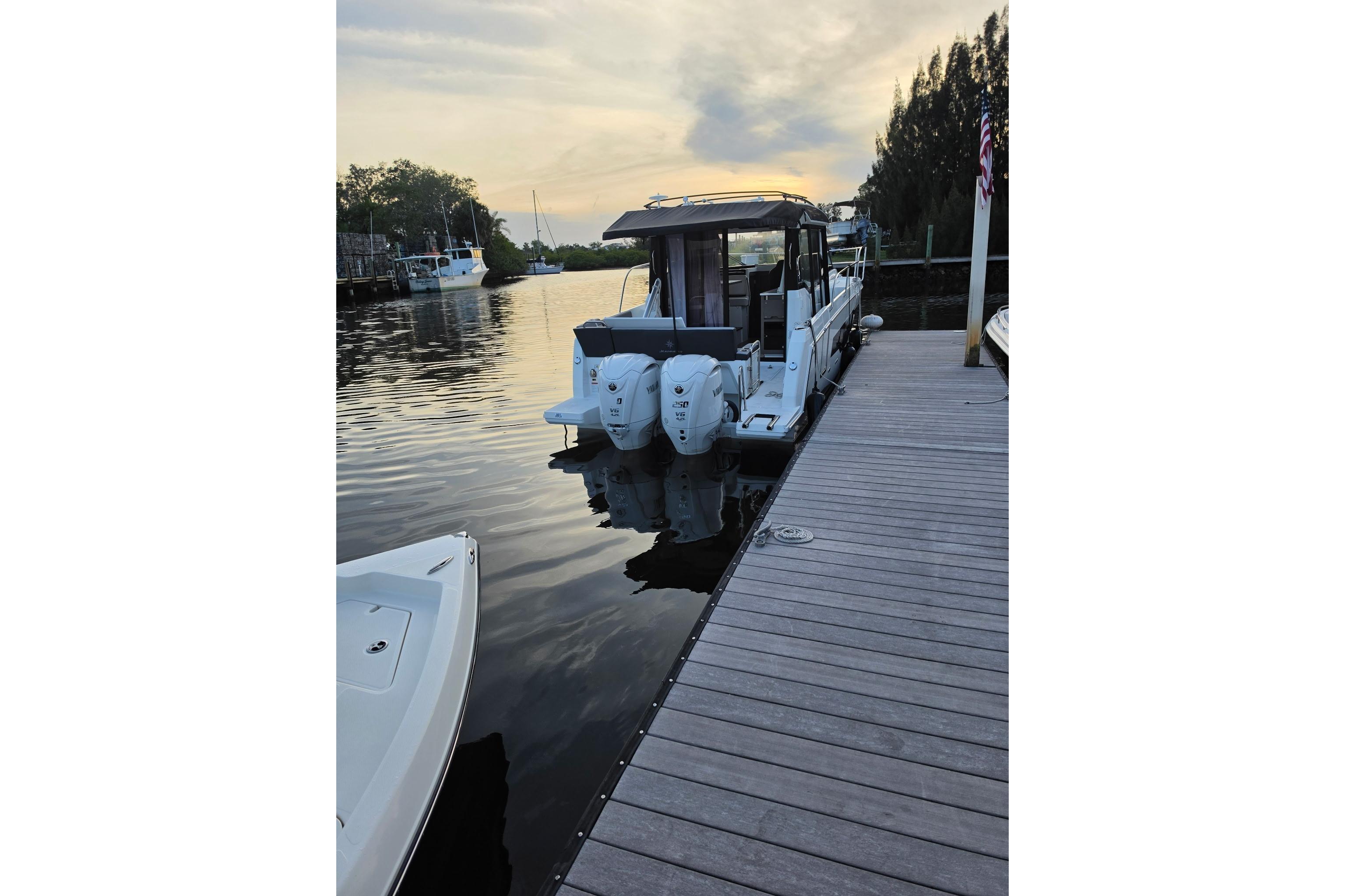 2026 Jeanneau NC 895 Series 2 docked at a serene marina during sunset.