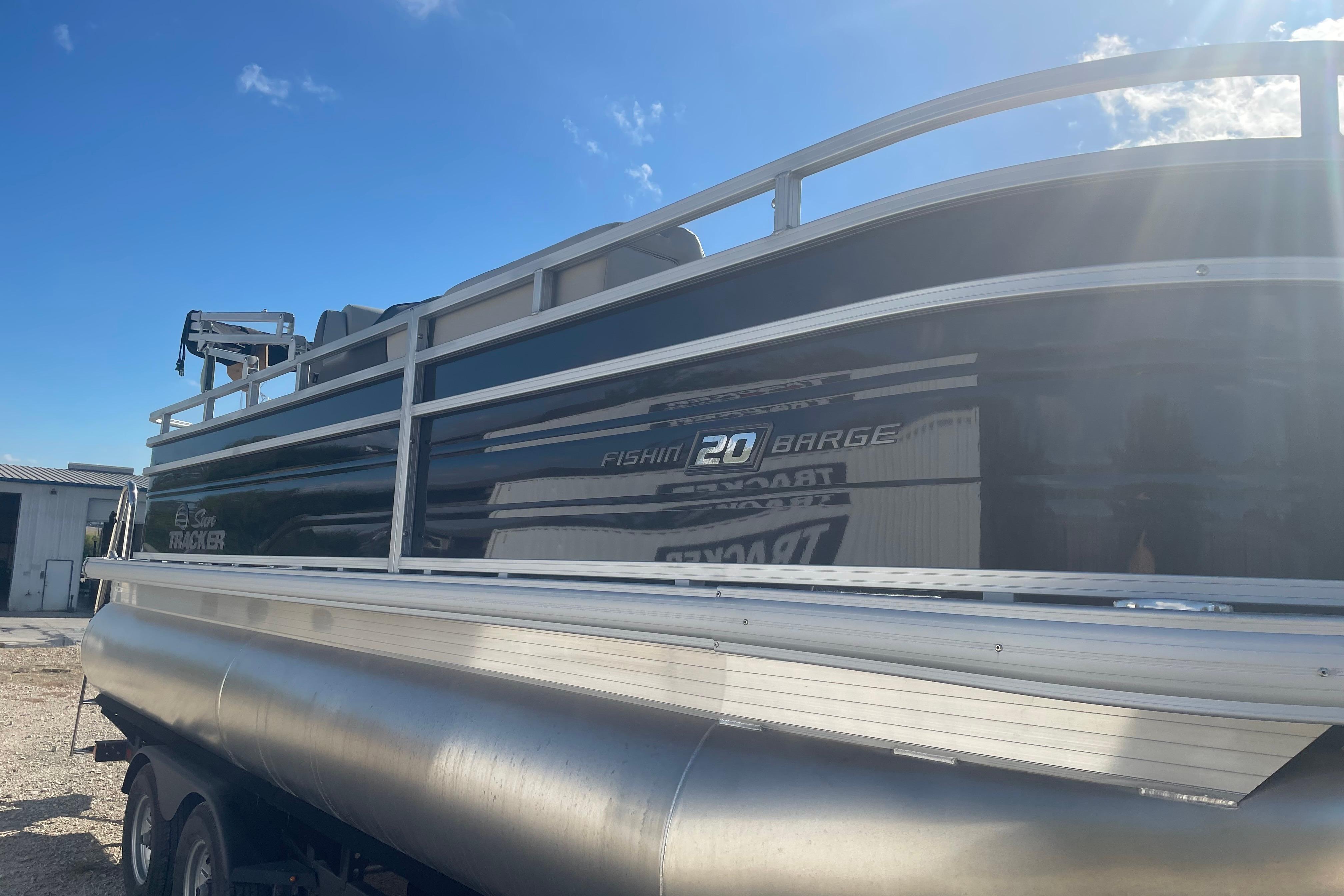2026 Sun Tracker Fishin' Barge 20 DLX pontoon boat under clear blue sky.
