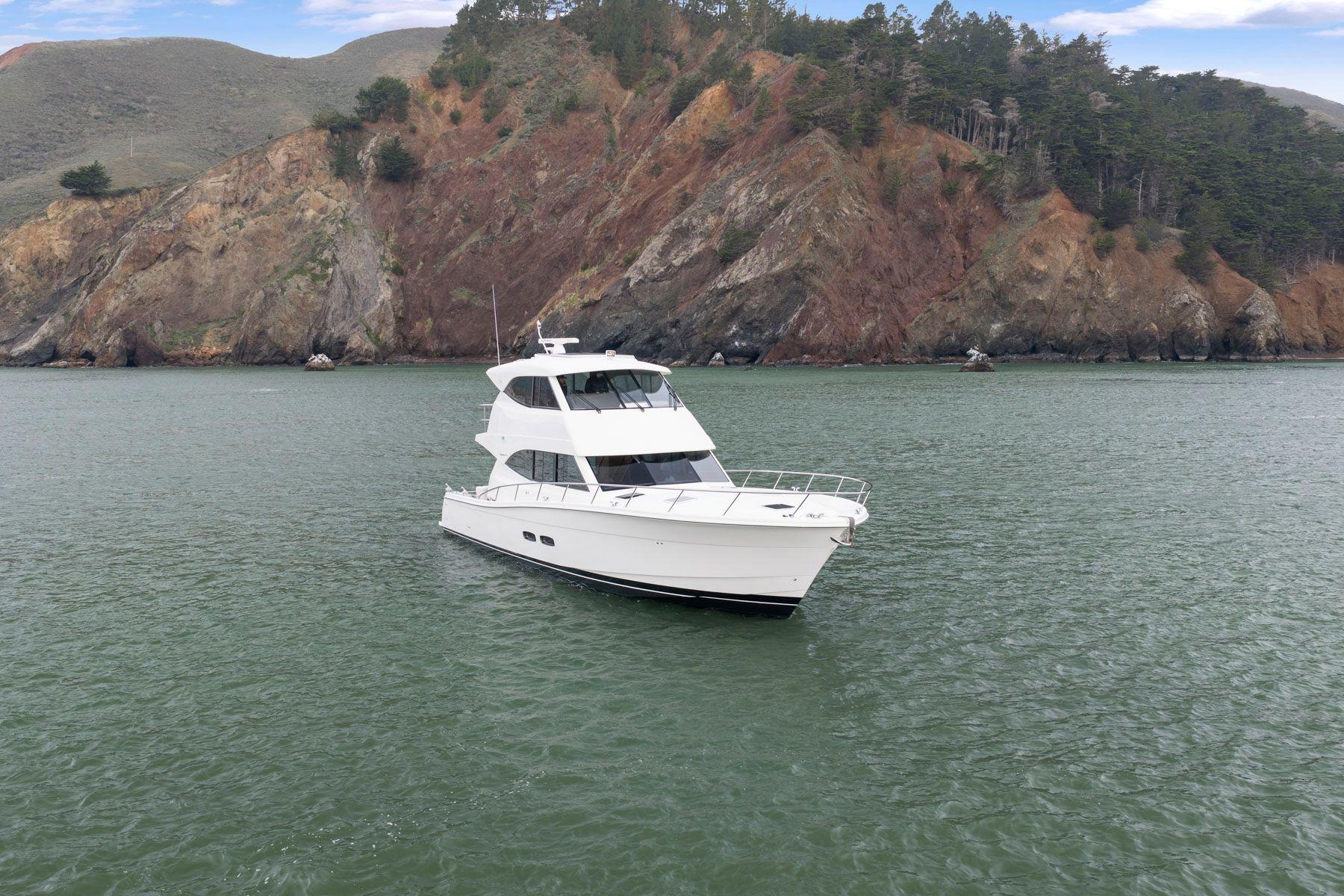 2014 Maritimo M50 yacht on calm water with rocky hillside backdrop.