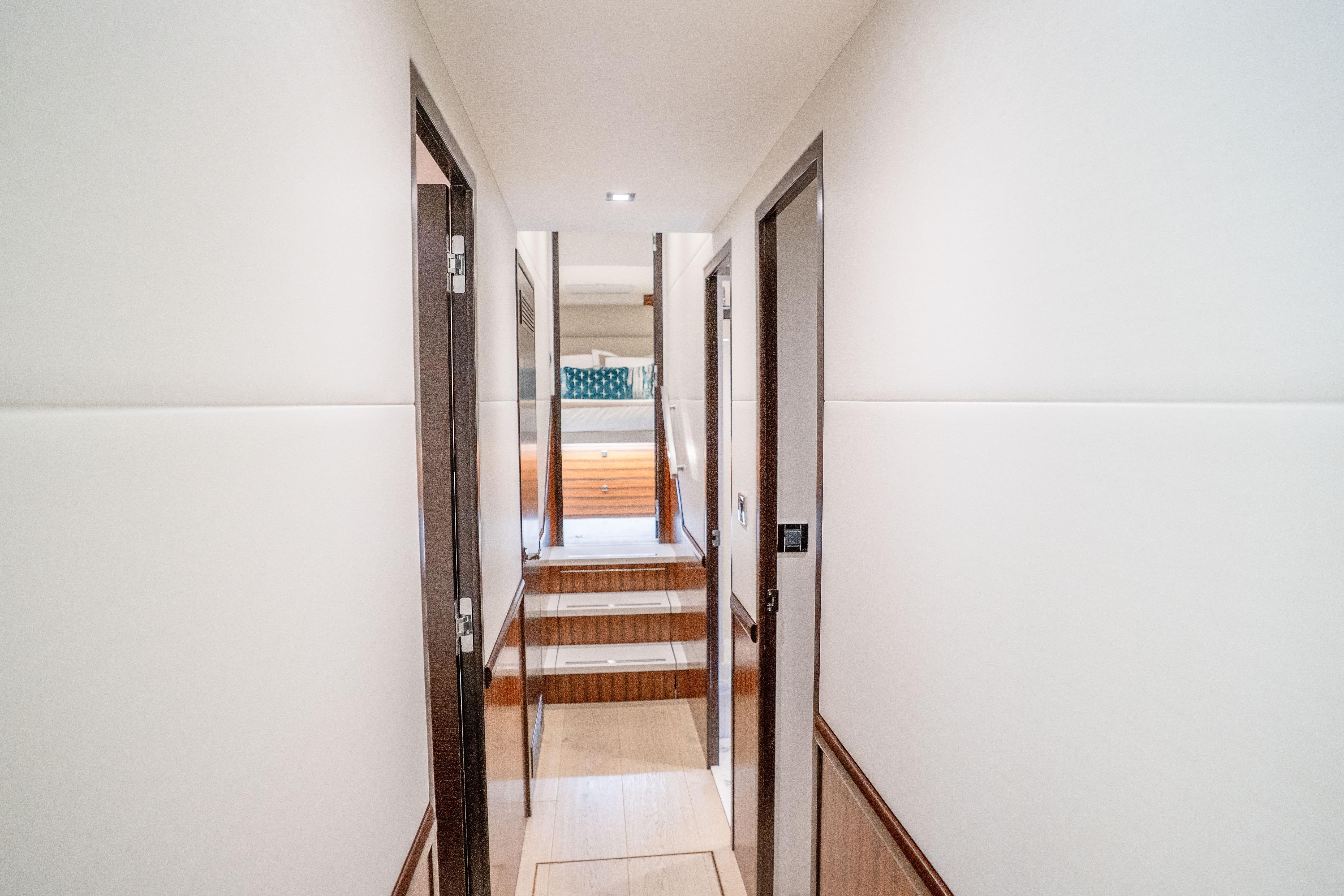 Hallway inside 2021 Hatteras M75 Panacera yacht, featuring modern design and wood accents.