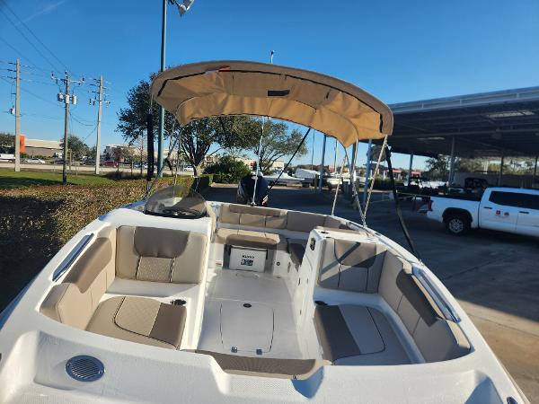 2025 Tahoe 1950 boat with beige seating and canopy, parked outdoors.