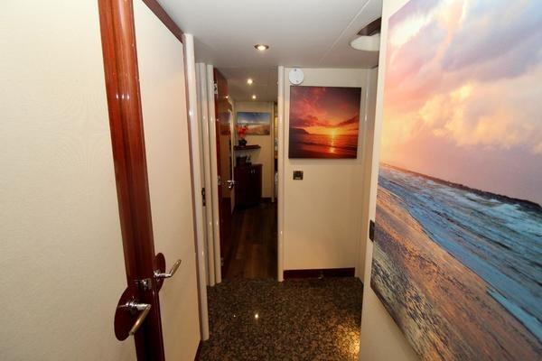 Hallway of 2007 Lazzara 68 yacht with ocean-themed artwork and elegant wood finishes.