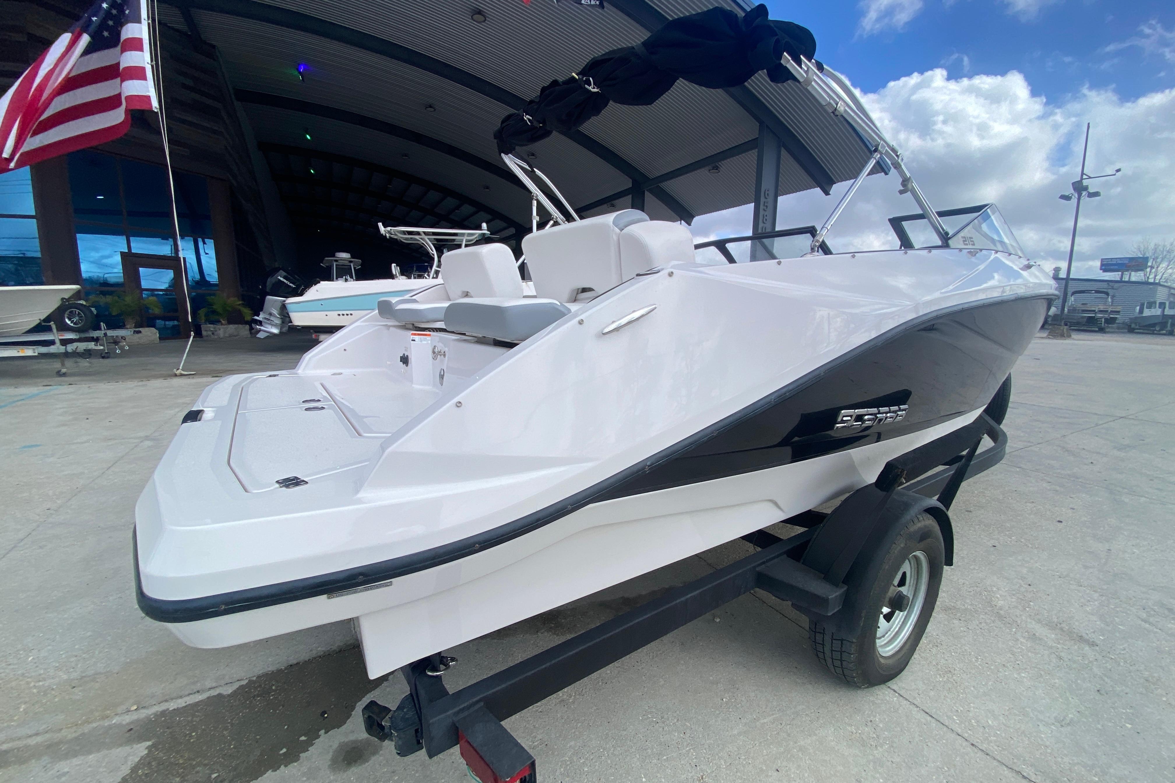 2018 Scarab 215 G boat on trailer, displayed outdoors with American flag.