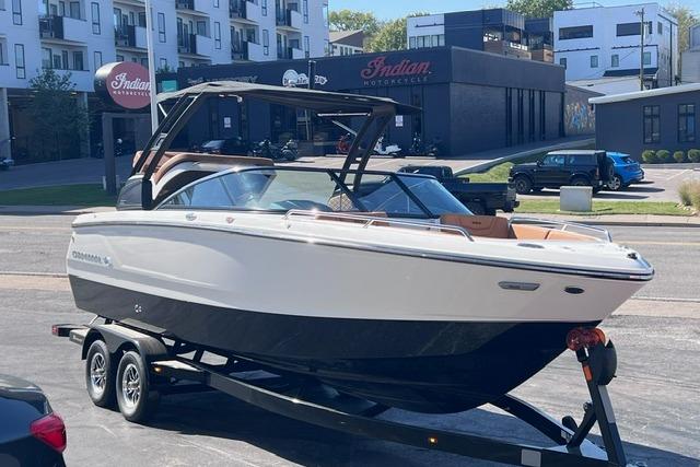 2025 Chaparral 247 SSX boat on trailer in urban setting, near Indian Motorcycle shop.