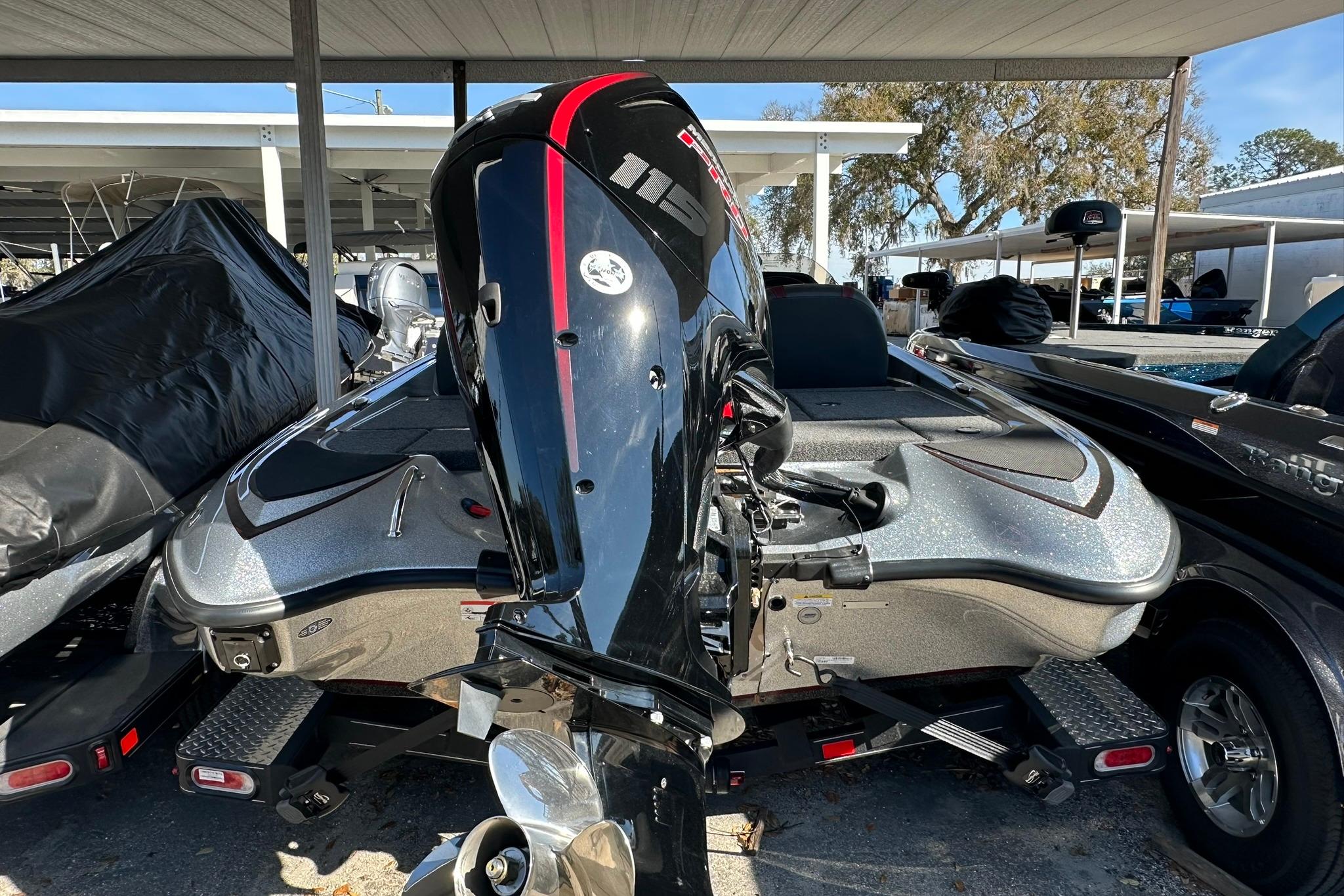 2026 Triton 179 TrX boat with powerful outboard motor, parked under a canopy.