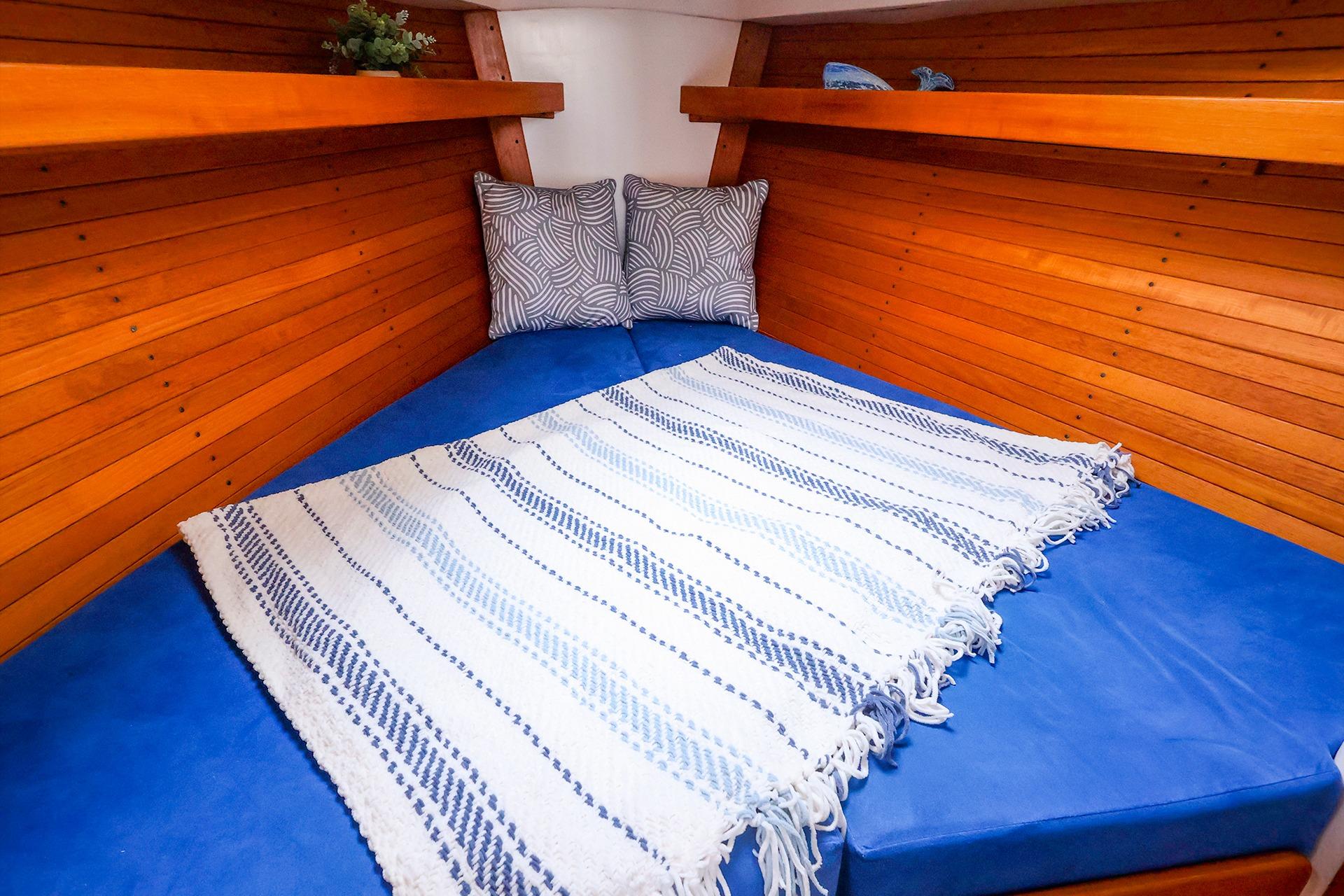 Cozy cabin interior of 2001 J Boats J/32 with blue cushions and striped blanket.