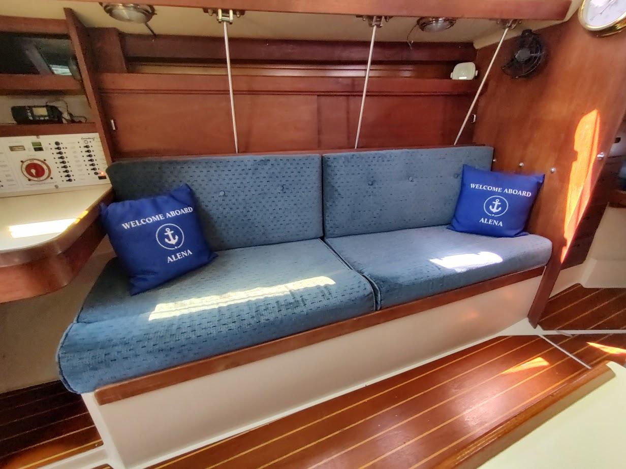 Interior of 1987 Catalina C-34 sailboat with blue cushions and "Welcome Aboard" pillows.