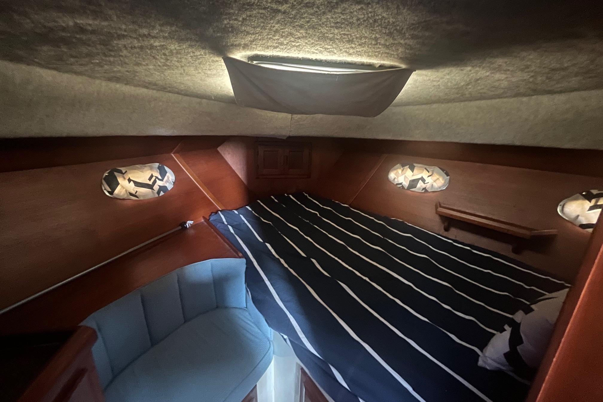 Cozy cabin interior of 1990 Cooper Prowler 35 with striped bedding and wooden accents.