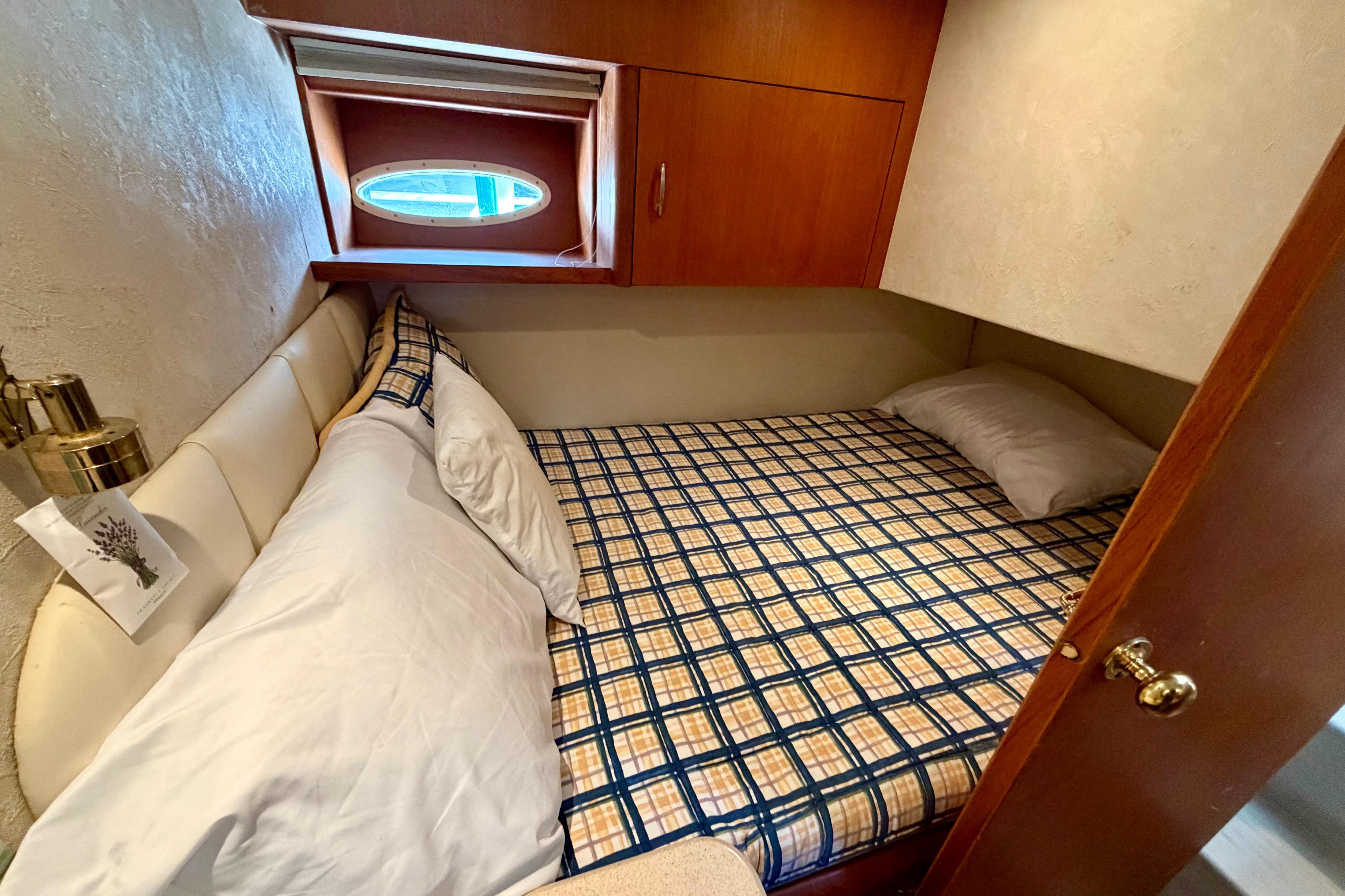 Cozy cabin bedroom in 1999 Ocean 40 Express yacht with plaid bedding and wooden accents.