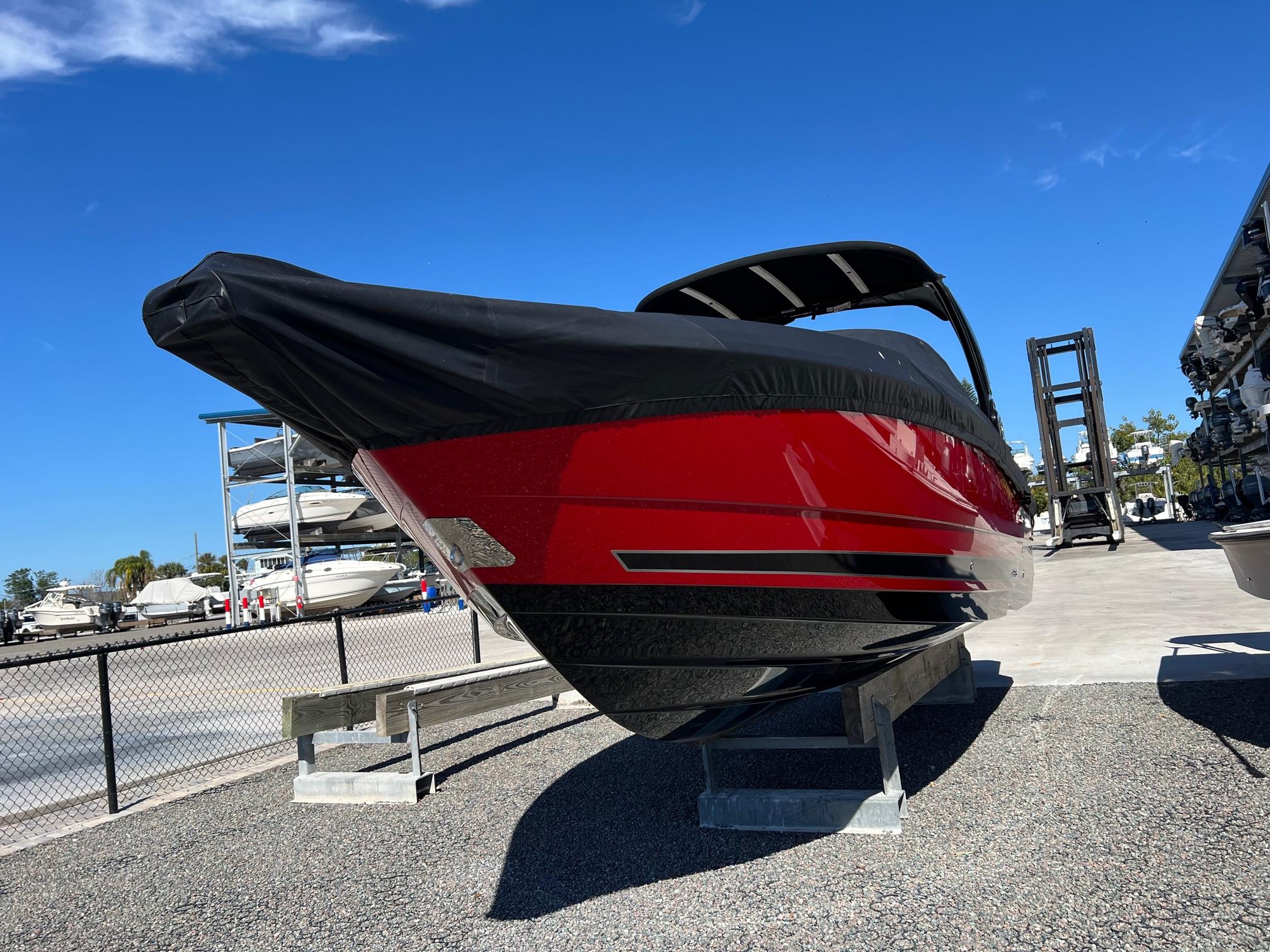 2021 Monterey 275 Super Sport boat, red and black, docked outdoors under clear blue sky.