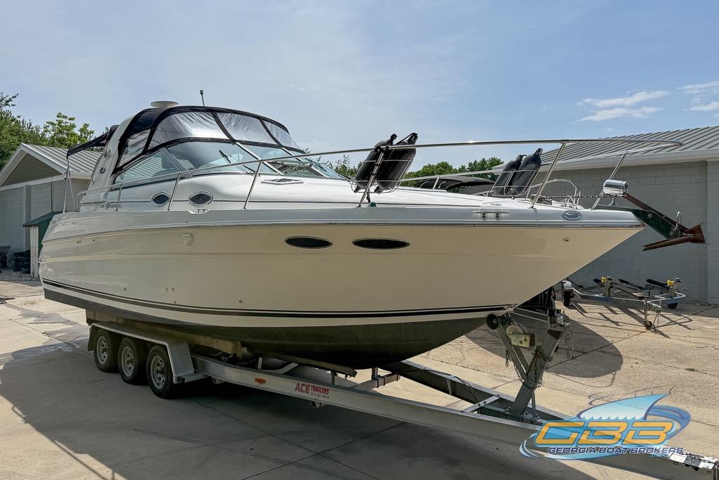 1999 Sea Ray 290 Sundancer boat on trailer, parked outdoors near a building.