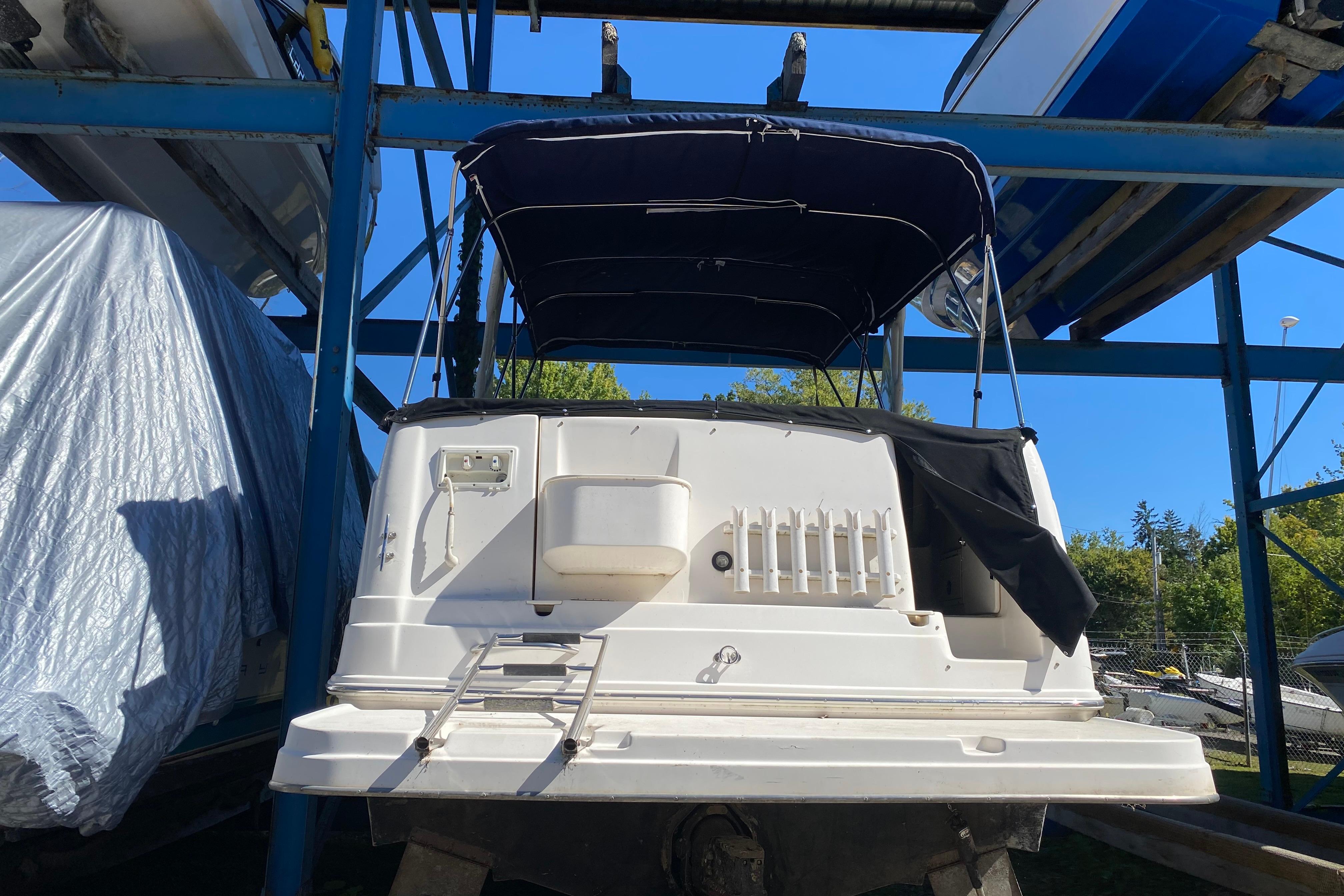 2003 Rinker Fiesta Vee 270 boat in storage, rear view with canopy and ladder.