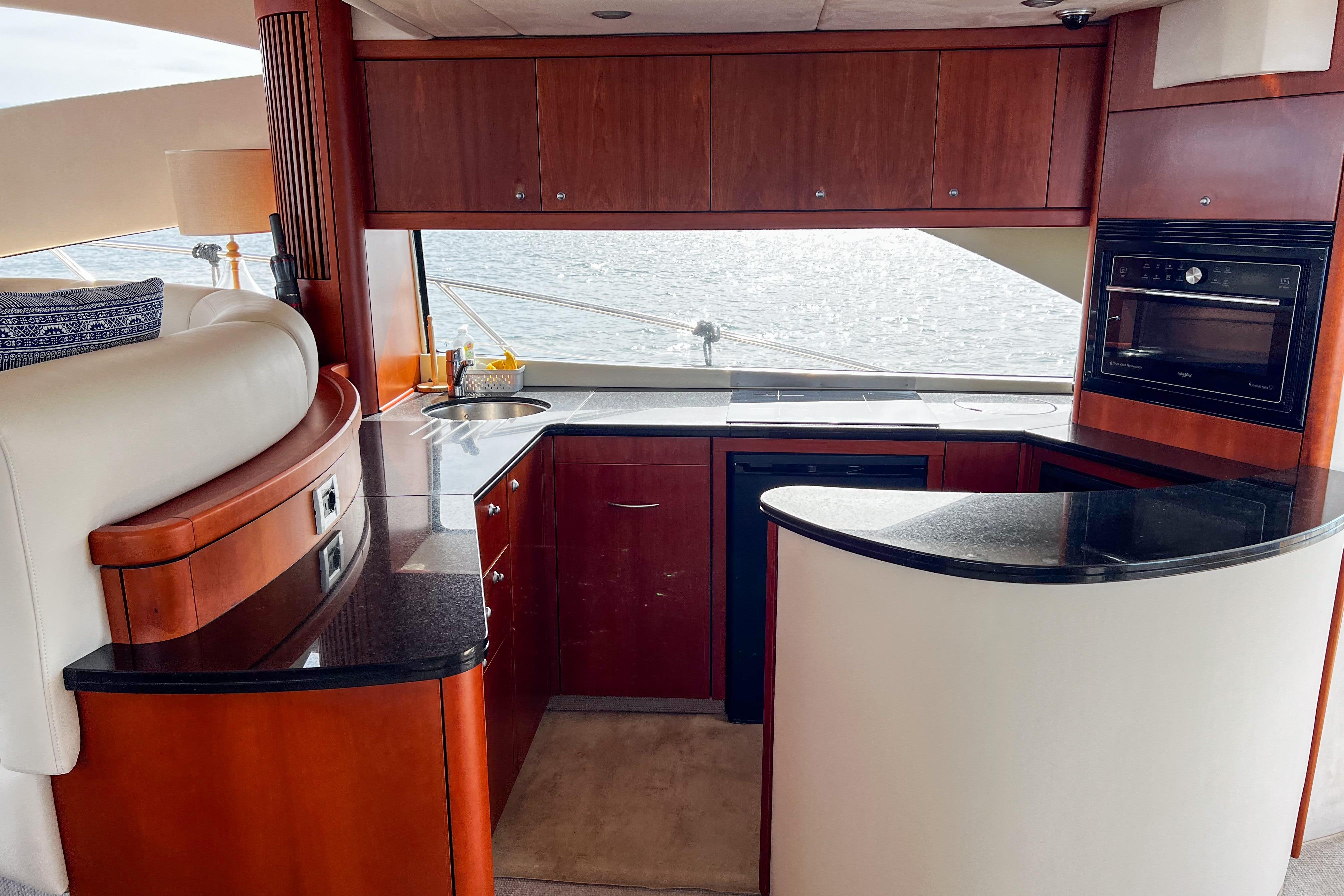 Luxurious kitchen interior of 2007 Sunseeker Manhattan 66 yacht with wood cabinetry and ocean view.