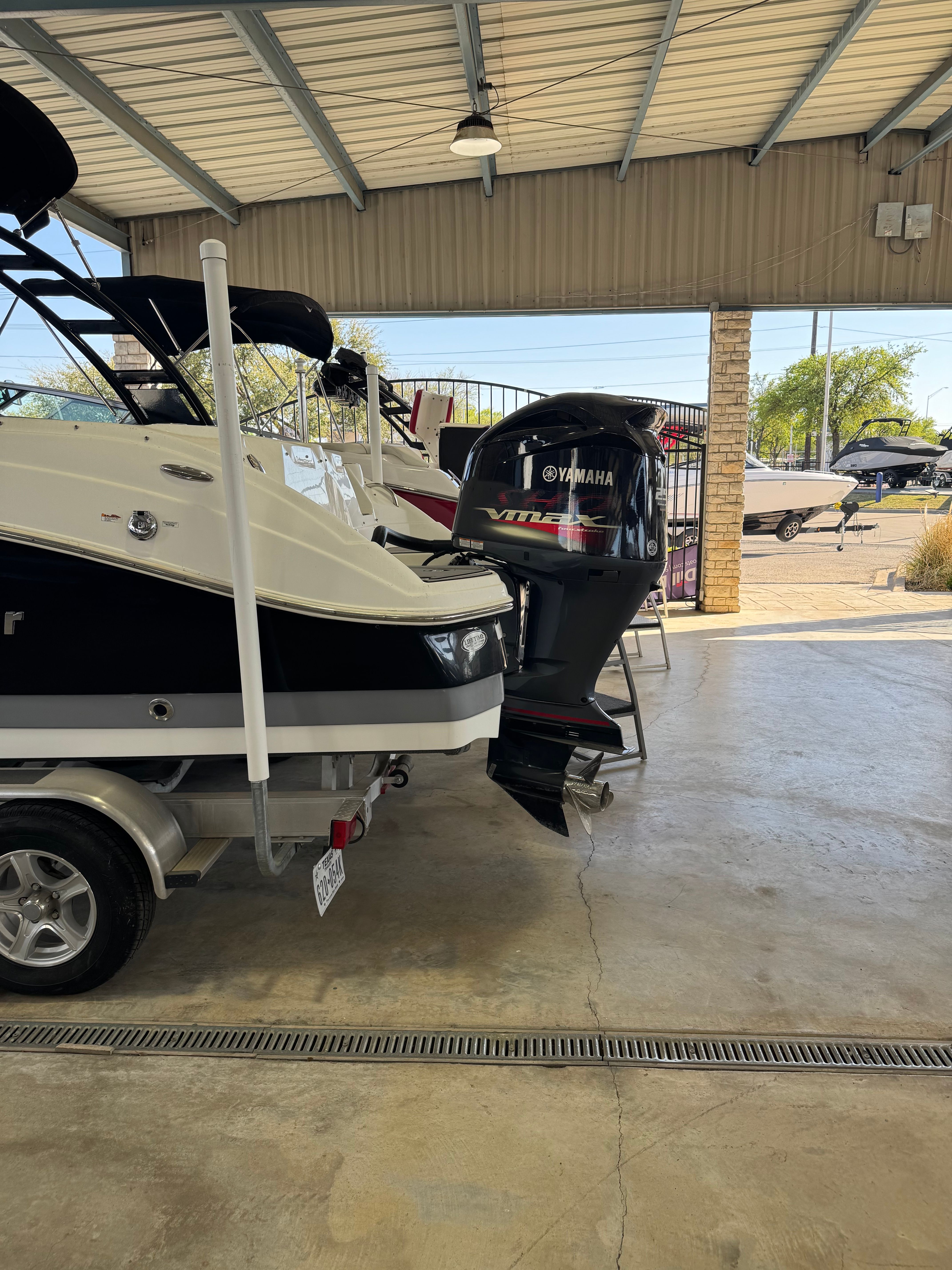 A 2021 NauticStar 243 DC boat is on a trailer in a covered area.