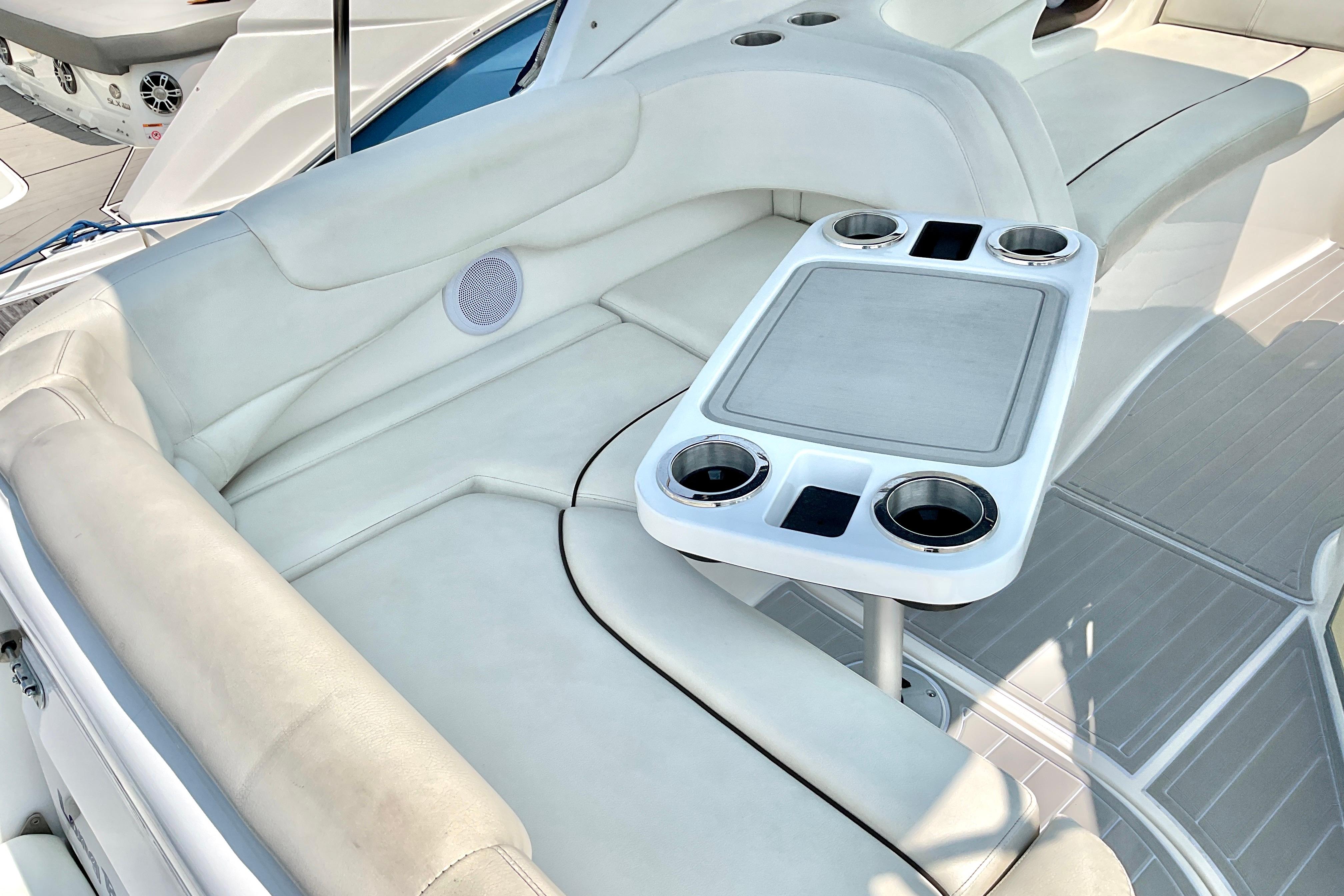 2013 Rinker 290 Express Cruiser interior with white seating and cupholder table.