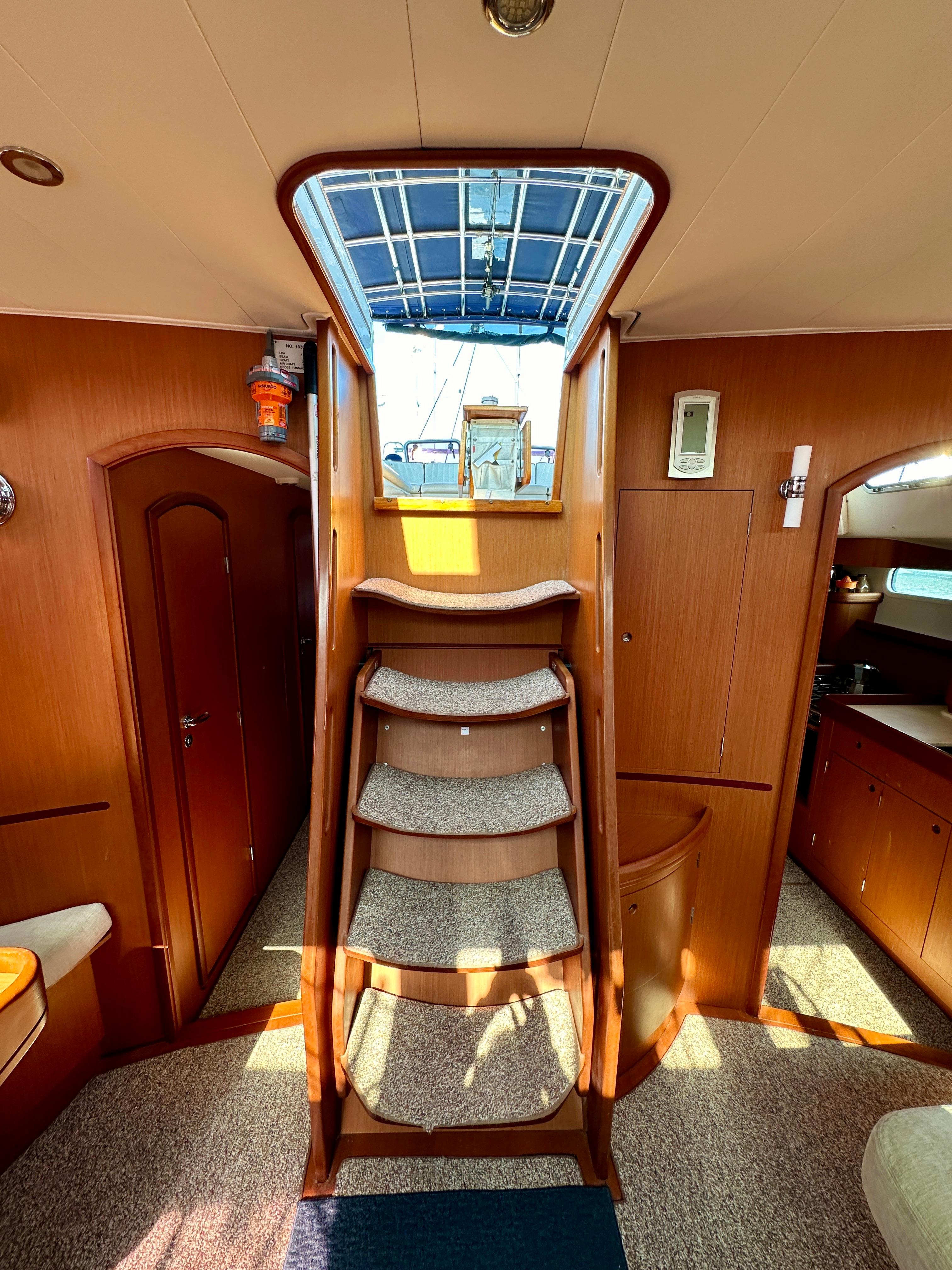 Interior of 2010 Beneteau 57 yacht with wooden stairs and cozy cabin design.