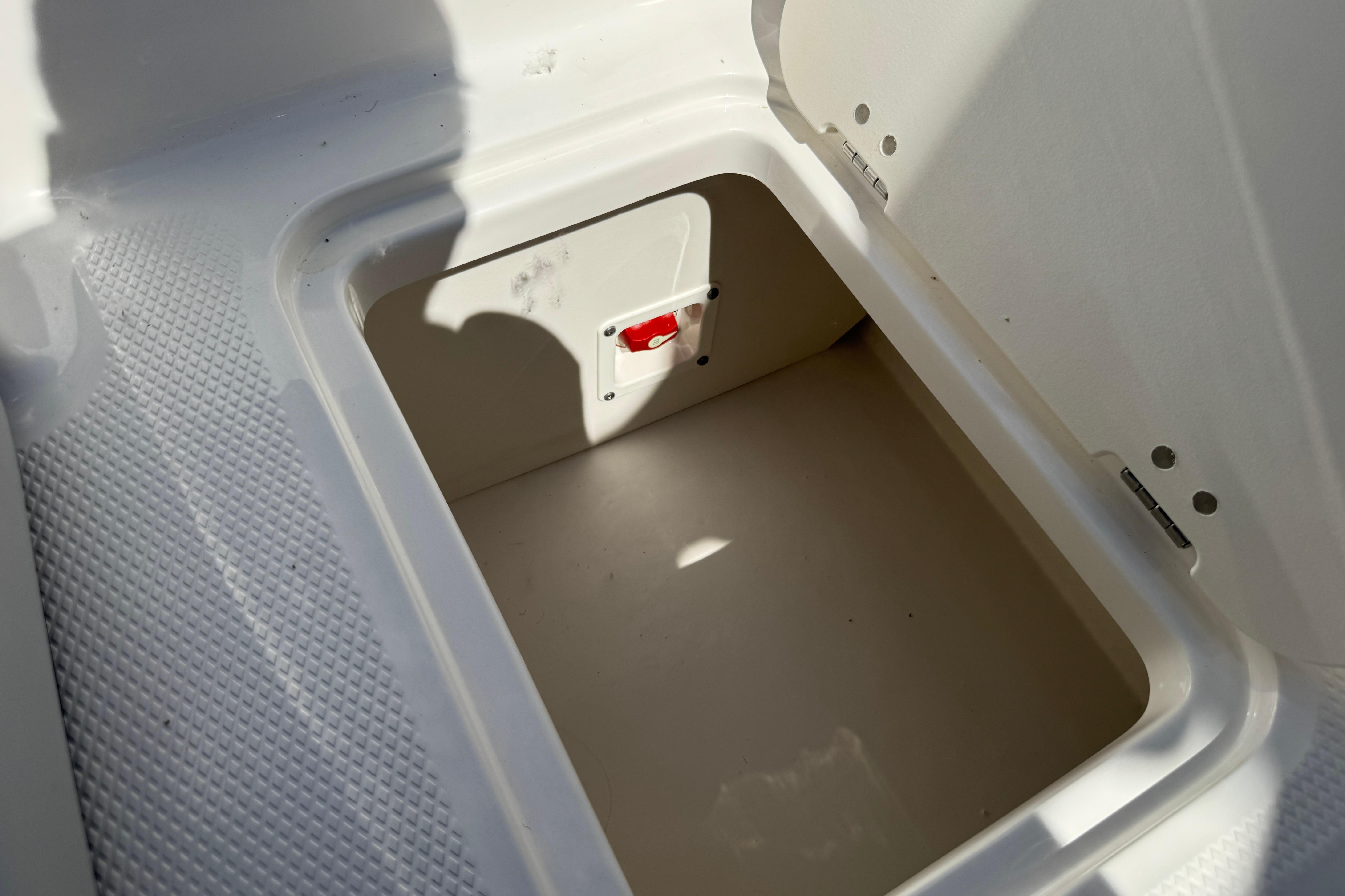 Storage compartment in 2026 Chaparral 21 SSi boat, featuring textured flooring and secure latch.