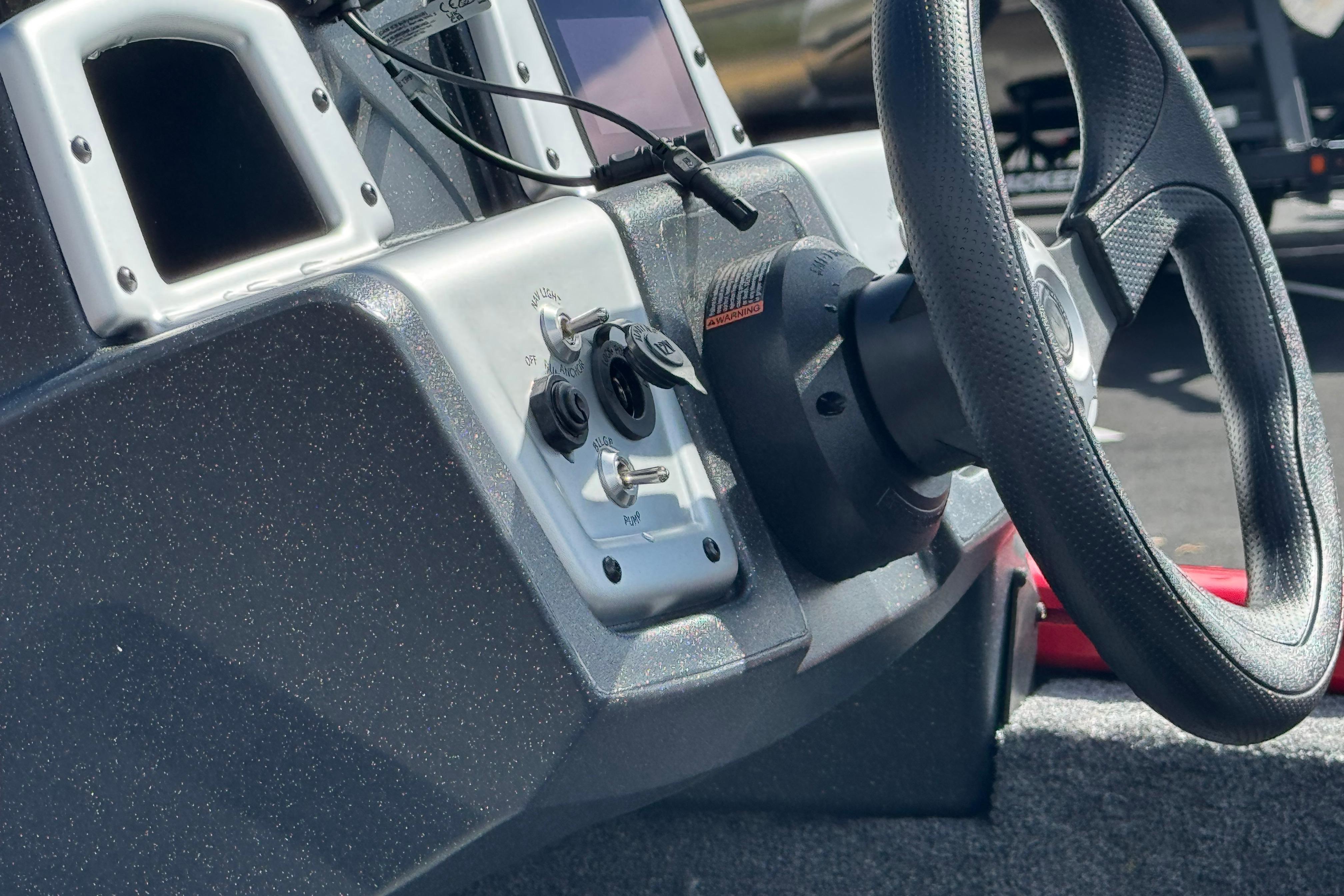 Steering console of 2026 Tracker Pro Team 175 boat with controls and steering wheel.