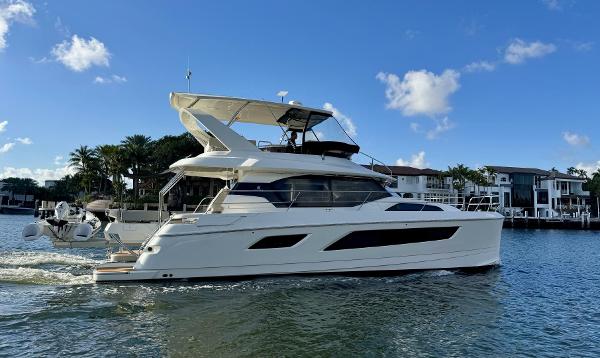 2022 Aquila 44 yacht cruising on a sunny day near waterfront homes.