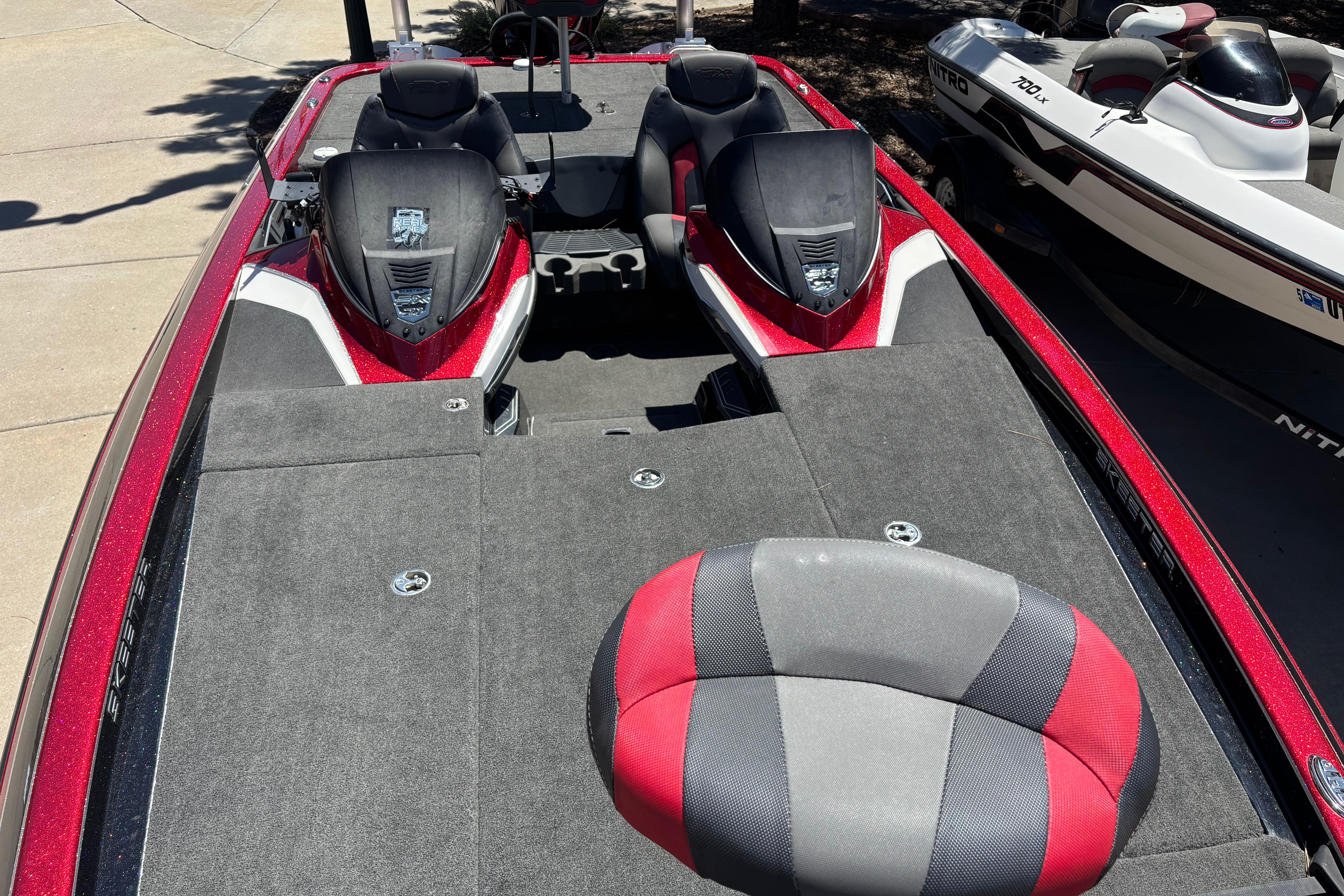2017 Skeeter FX21 bass boat with red and black seating, docked beside another boat.