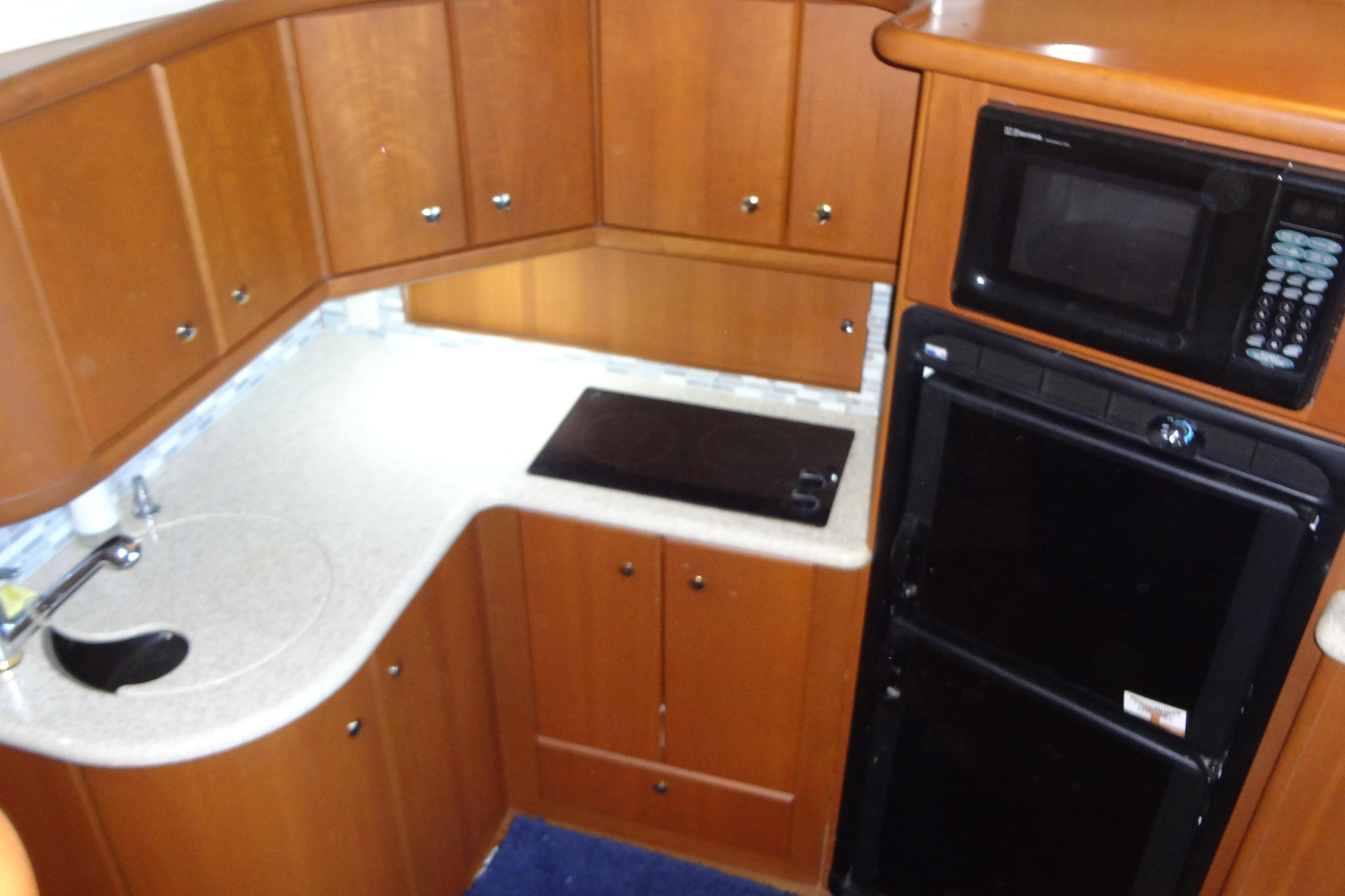 2005 Silverton 34 Convertible yacht kitchen with wood cabinets, microwave, and compact appliances.