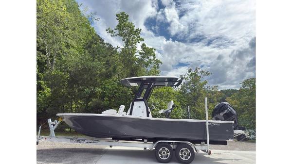 2025 Sea Fox 251 Bay Fox boat on trailer, surrounded by lush greenery and cloudy sky.