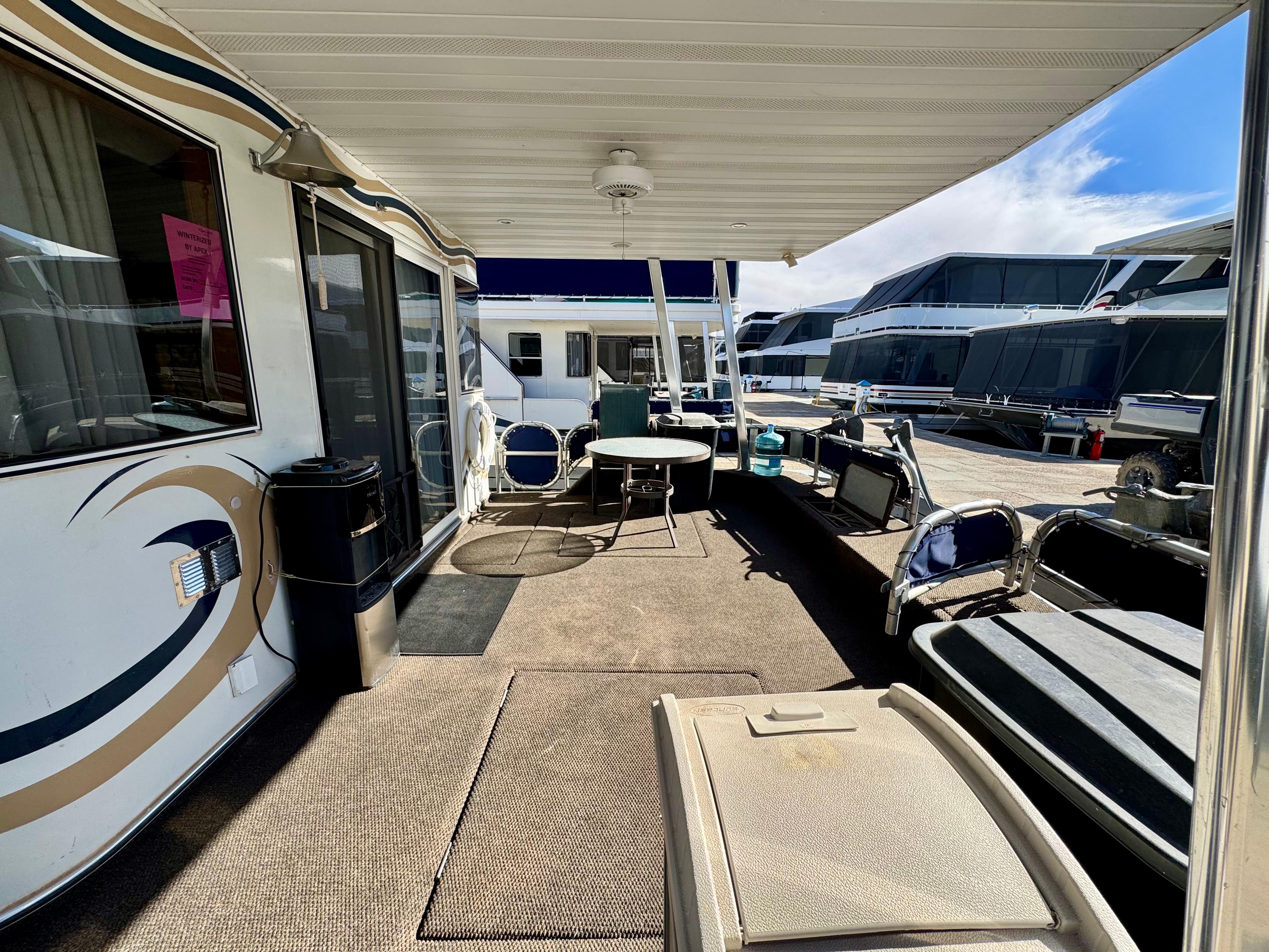 Houseboat deck with seating area, 2003 Sharpe Wailea Trip model, docked alongside other boats.