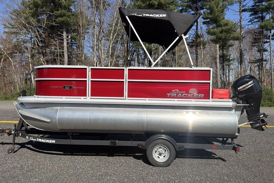 2026 Sun Tracker Party Barge 16 DLX pontoon boat on trailer, red and silver design.
