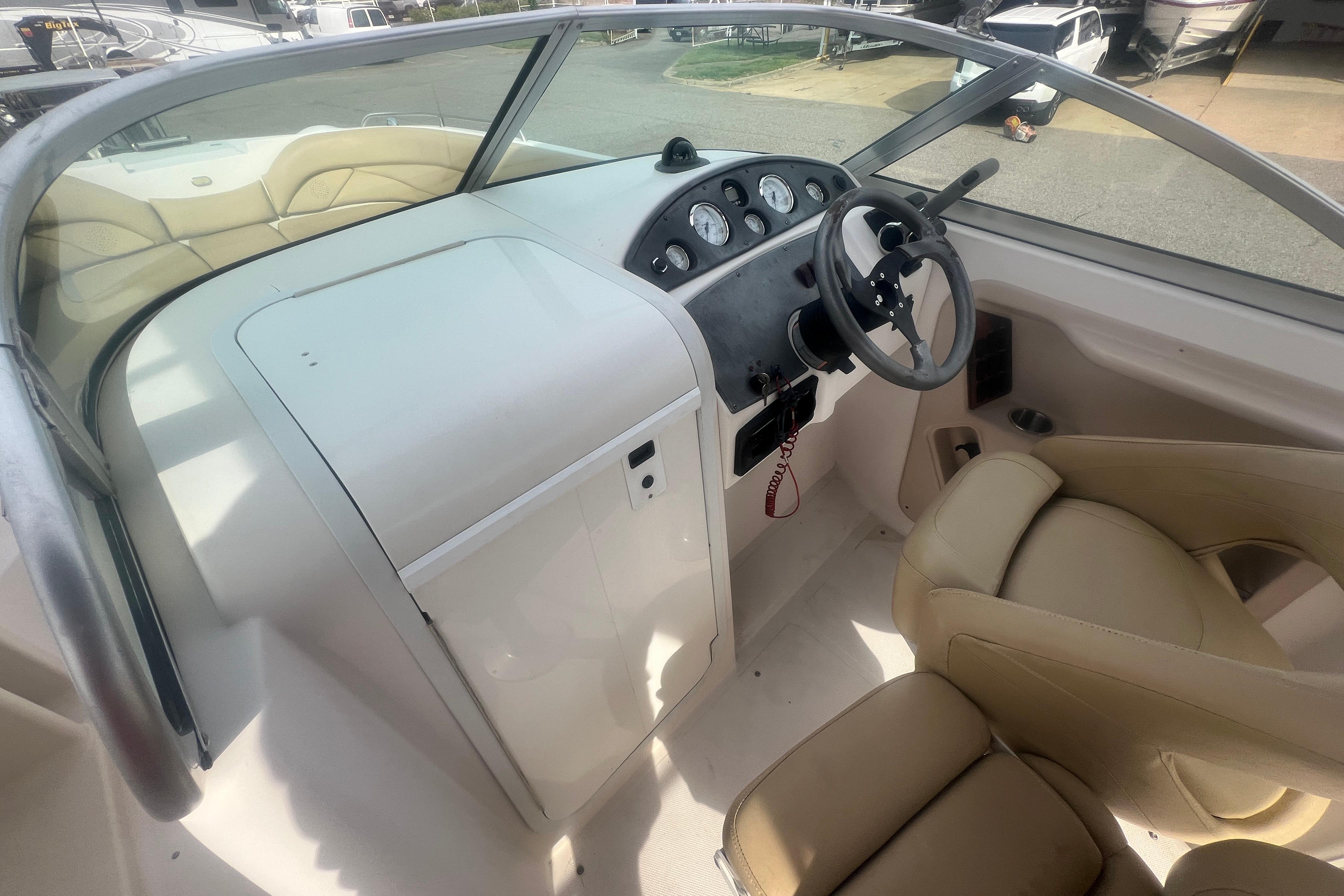 2002 Hurricane SunDeck 260 OB boat cockpit with steering wheel and beige seating.
