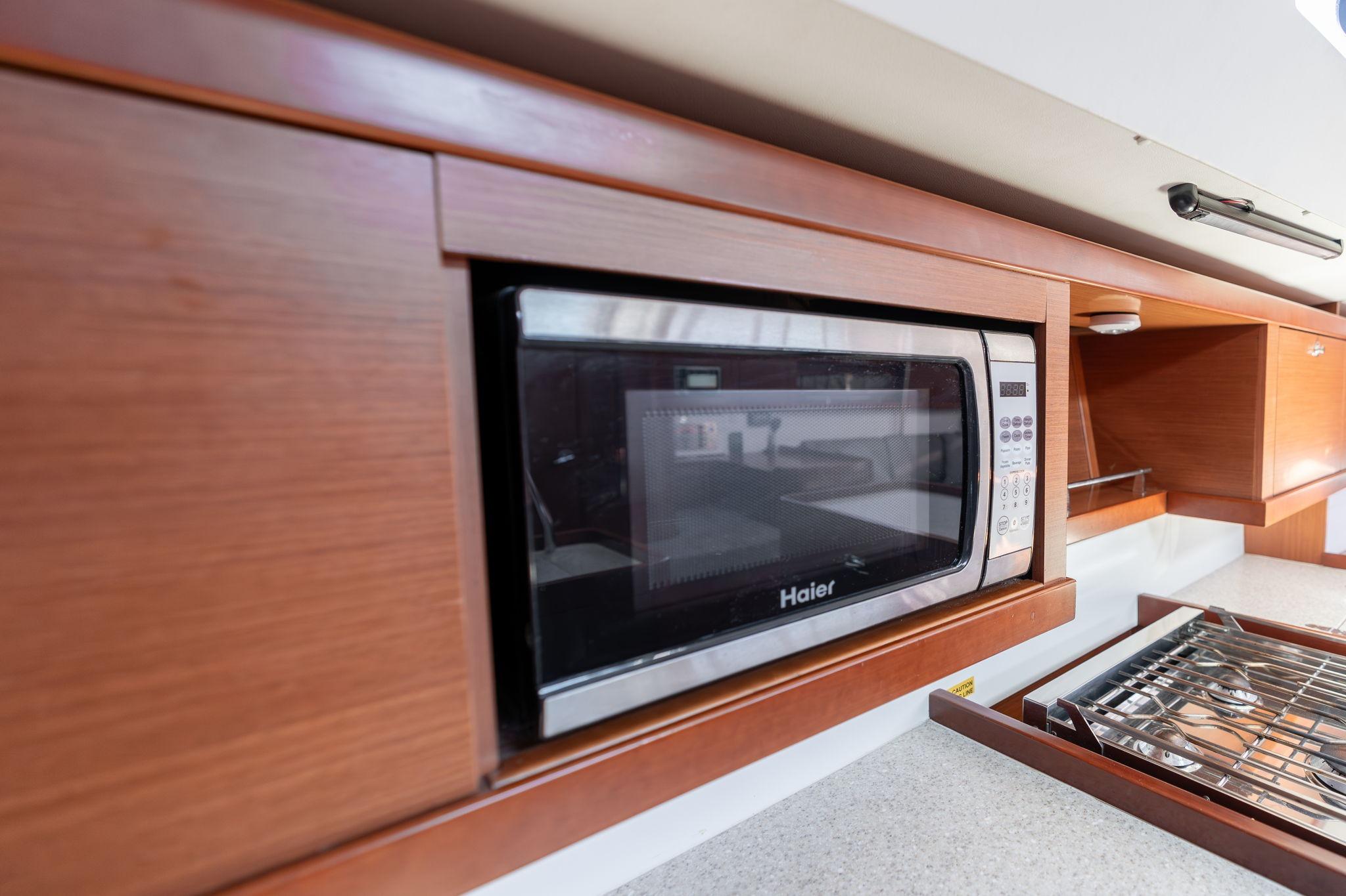 Microwave in 2013 Beneteau Oceanis 50 yacht kitchen with wooden cabinetry.
