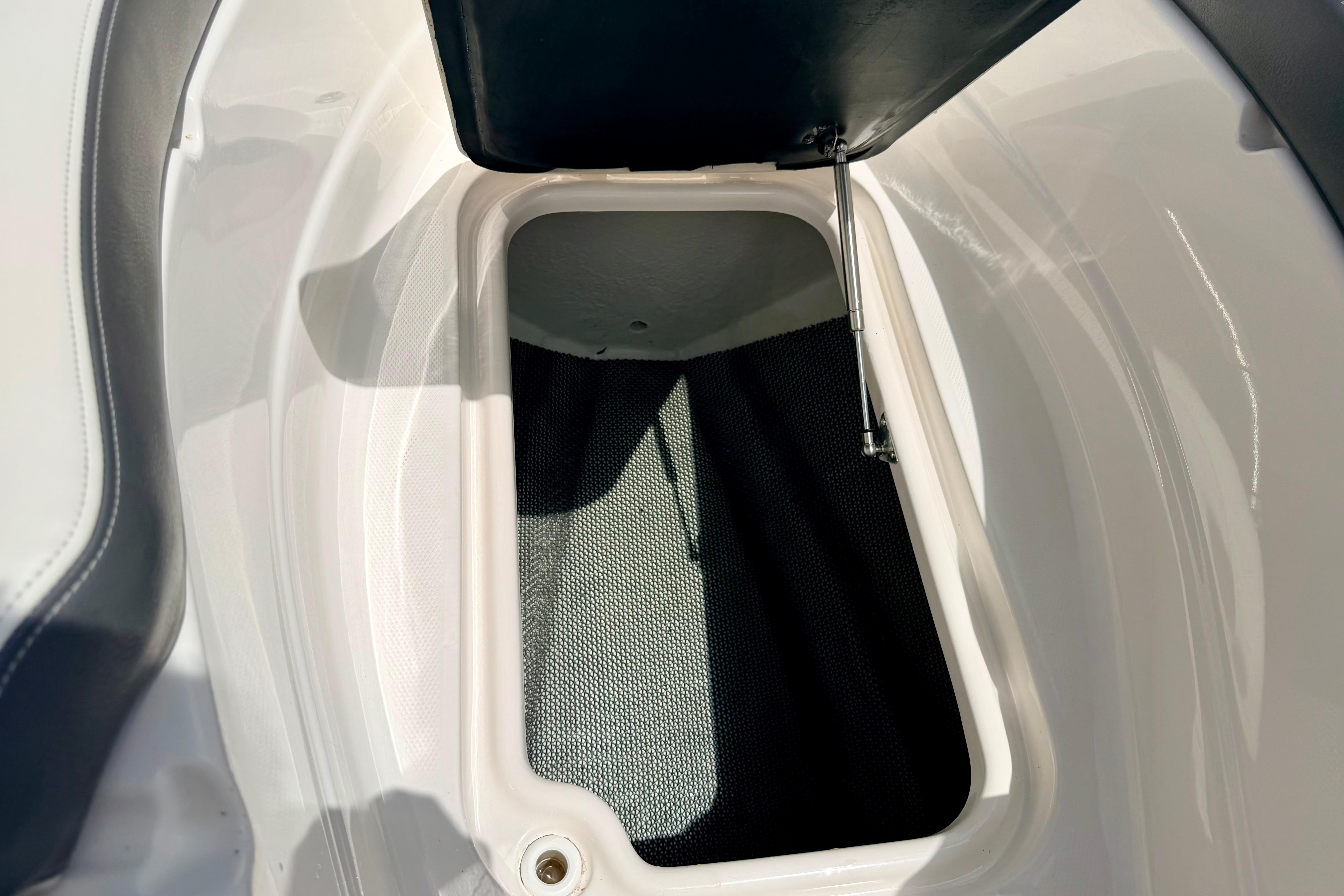Open storage compartment in 2015 Chaparral Sunesta 264 boat, featuring sleek white interior design.