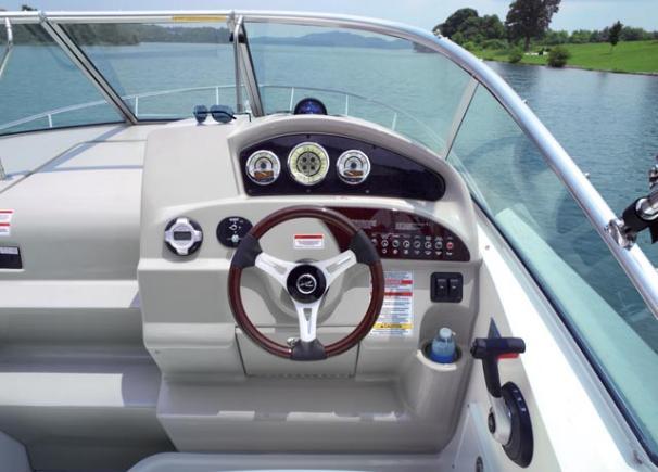2012 Sea Ray 240 Sundancer helm with steering wheel and gauges on a calm lake.