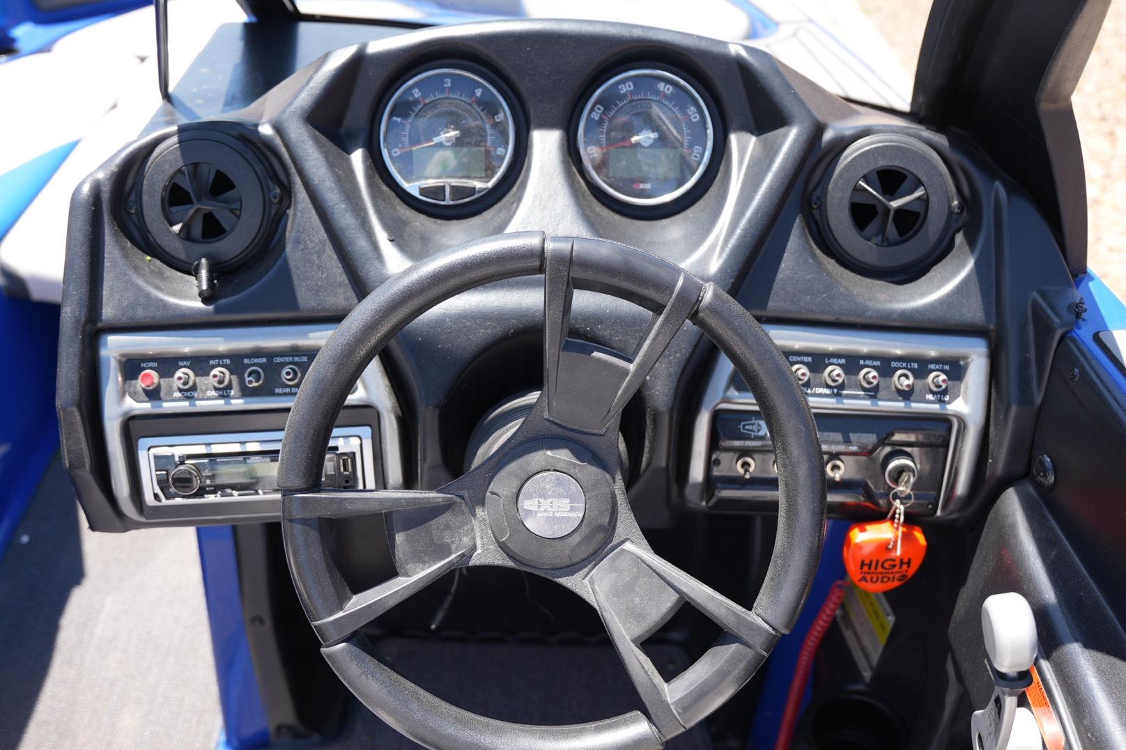 Steering wheel and dashboard of a 2015 Axis A24 boat, featuring gauges and controls.