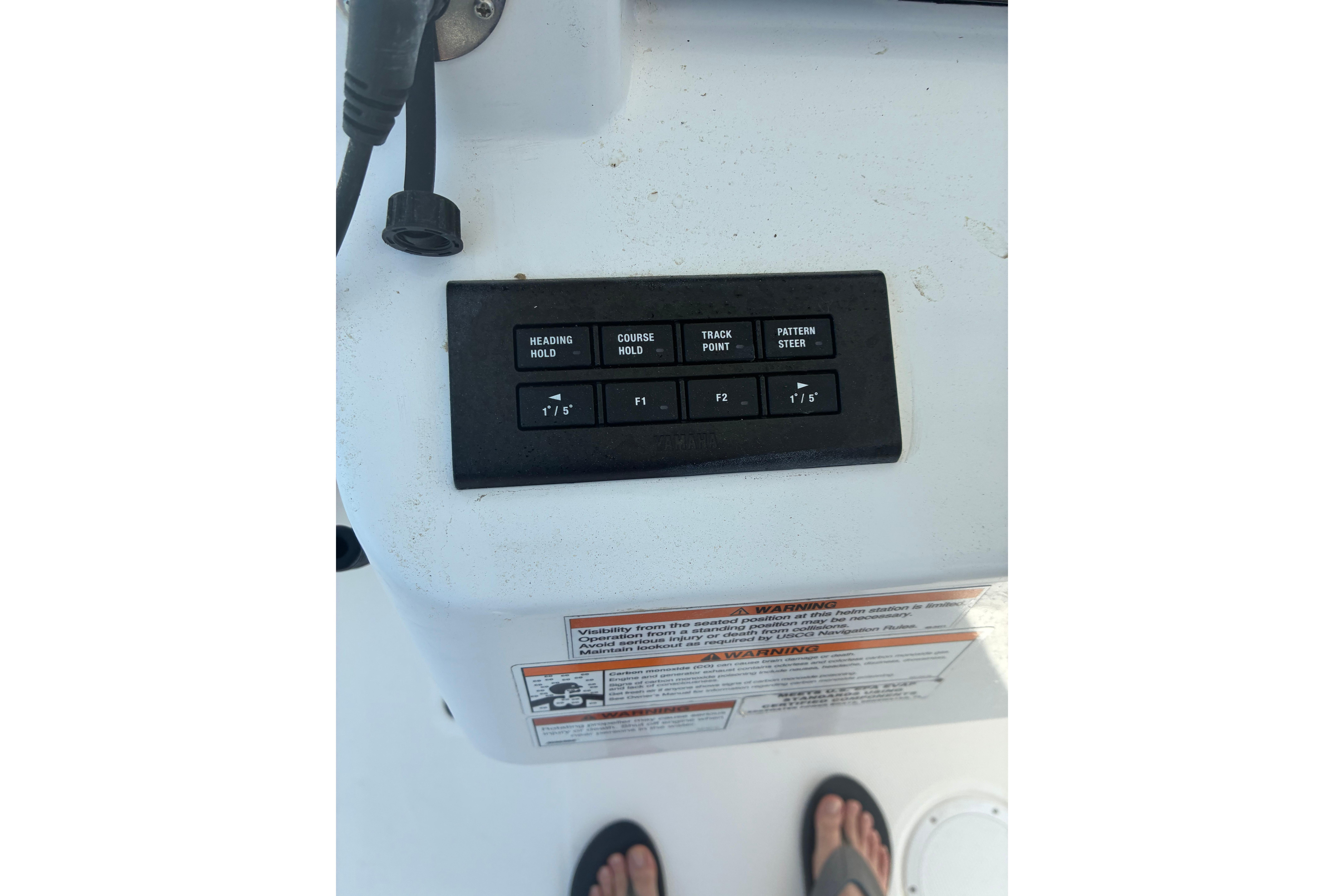 Control panel on 2023 Edgewater 285CC boat with navigation buttons and warning label.