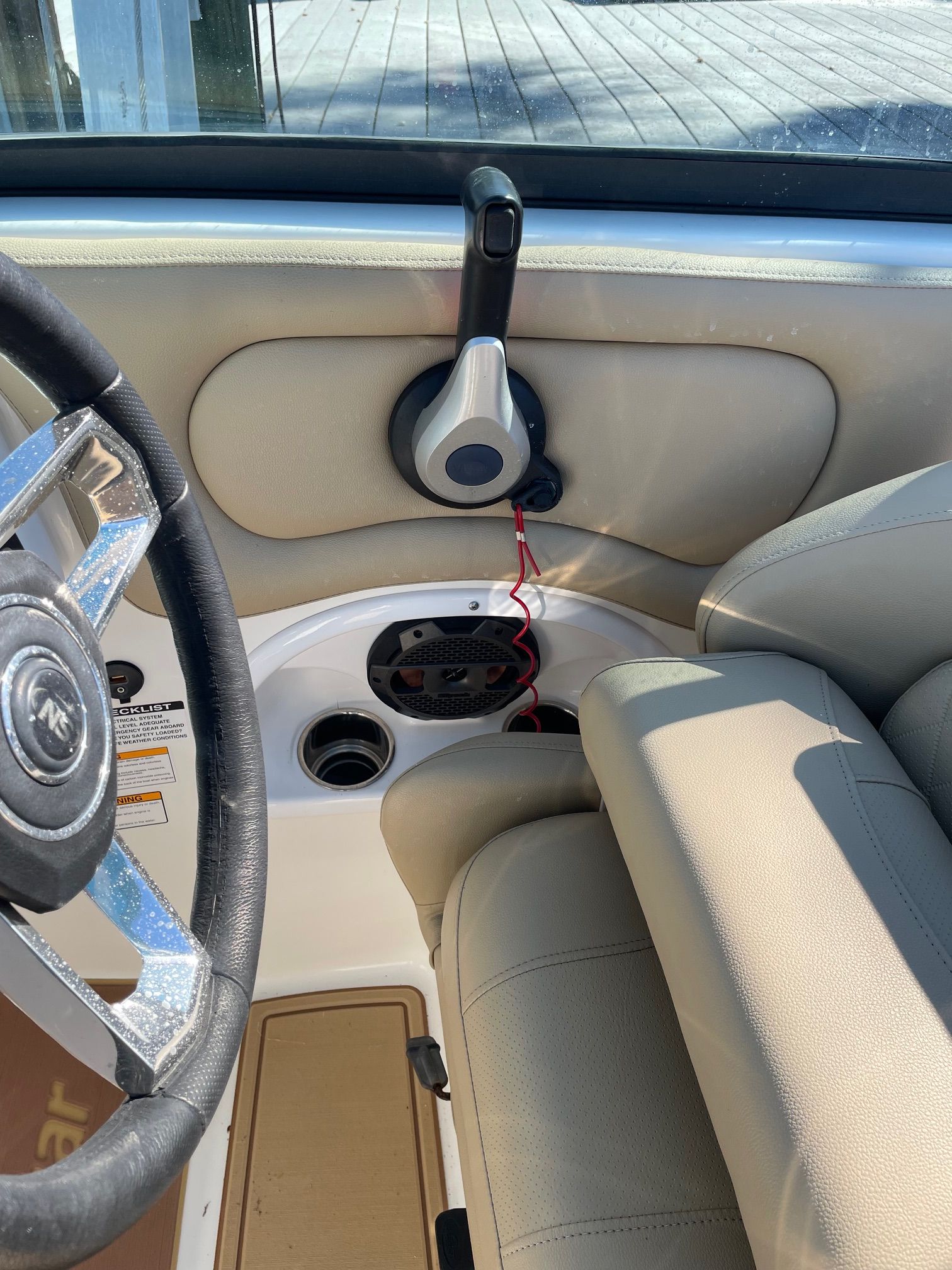 Interior view of a 2019 NauticStar 243DC Sport Deck with beige upholstery and steering wheel.