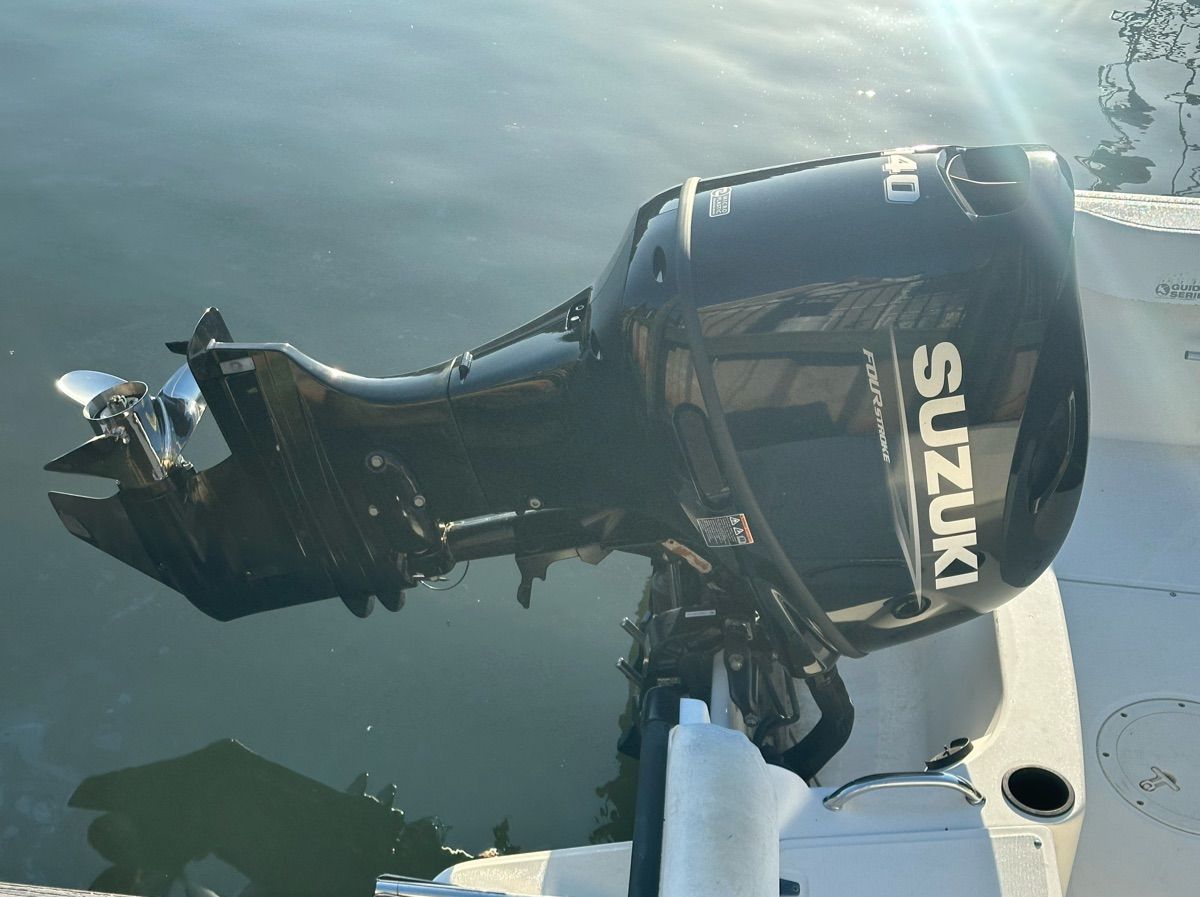A Suzuki outboard motor on a boat in calm water.