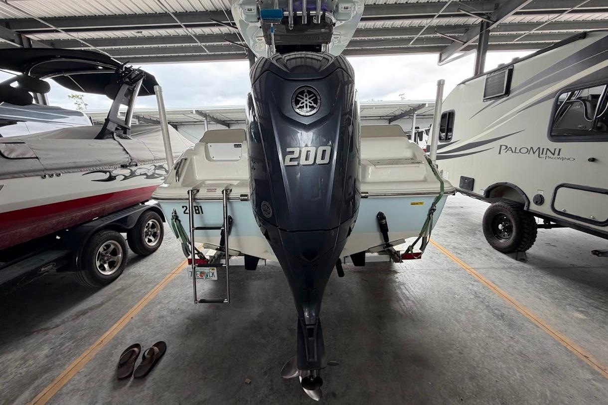 2024 Key West 219 FS boat with 200 HP engine in storage, surrounded by vehicles.