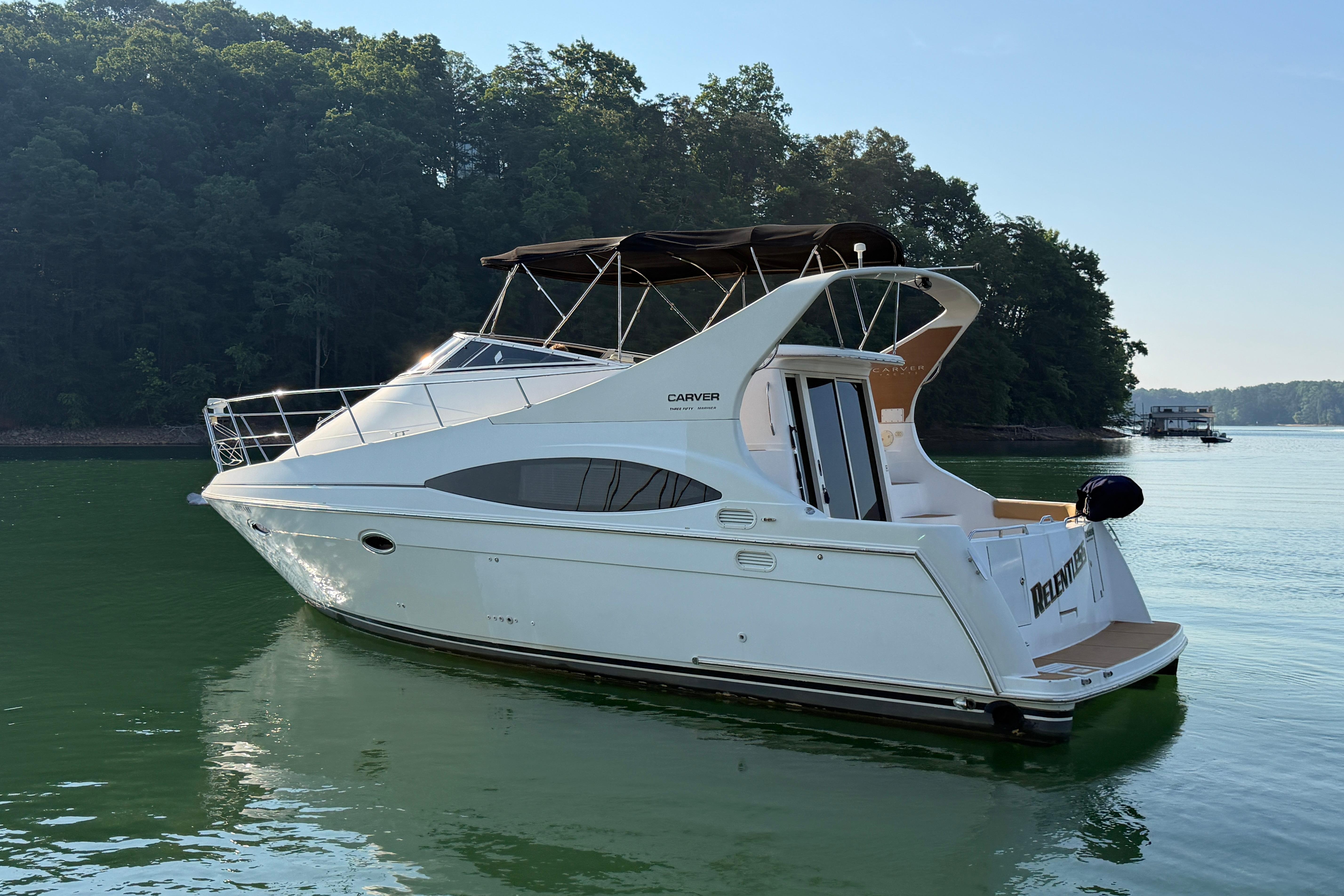 2003 Carver 350 Mariner yacht on serene lake with lush forest backdrop.