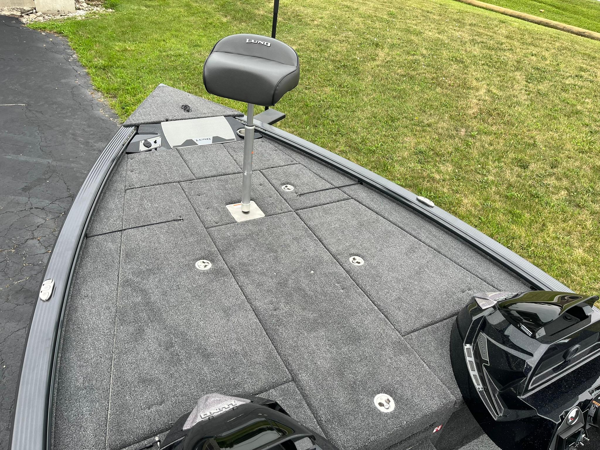 2026 Lund 1875 Pro-V Bass XS boat deck with seat, on grass.